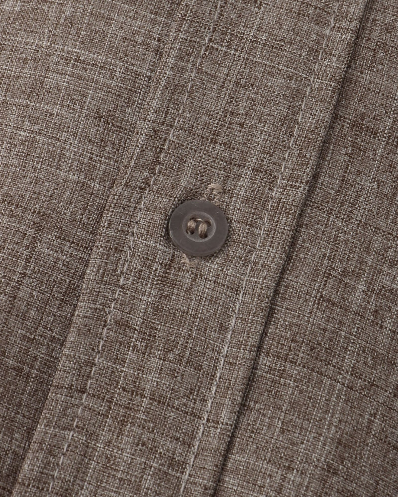 Close-up of a button on a textured brown fabric