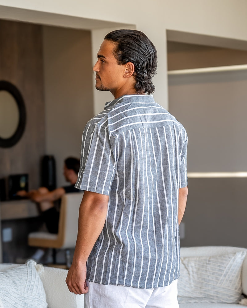 Man wearing a striped linen polo shirt standing in a living room.