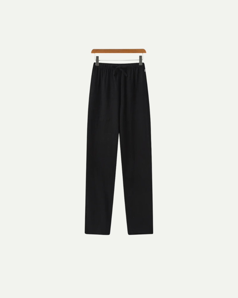 Black linen pants on a hanger against a white background