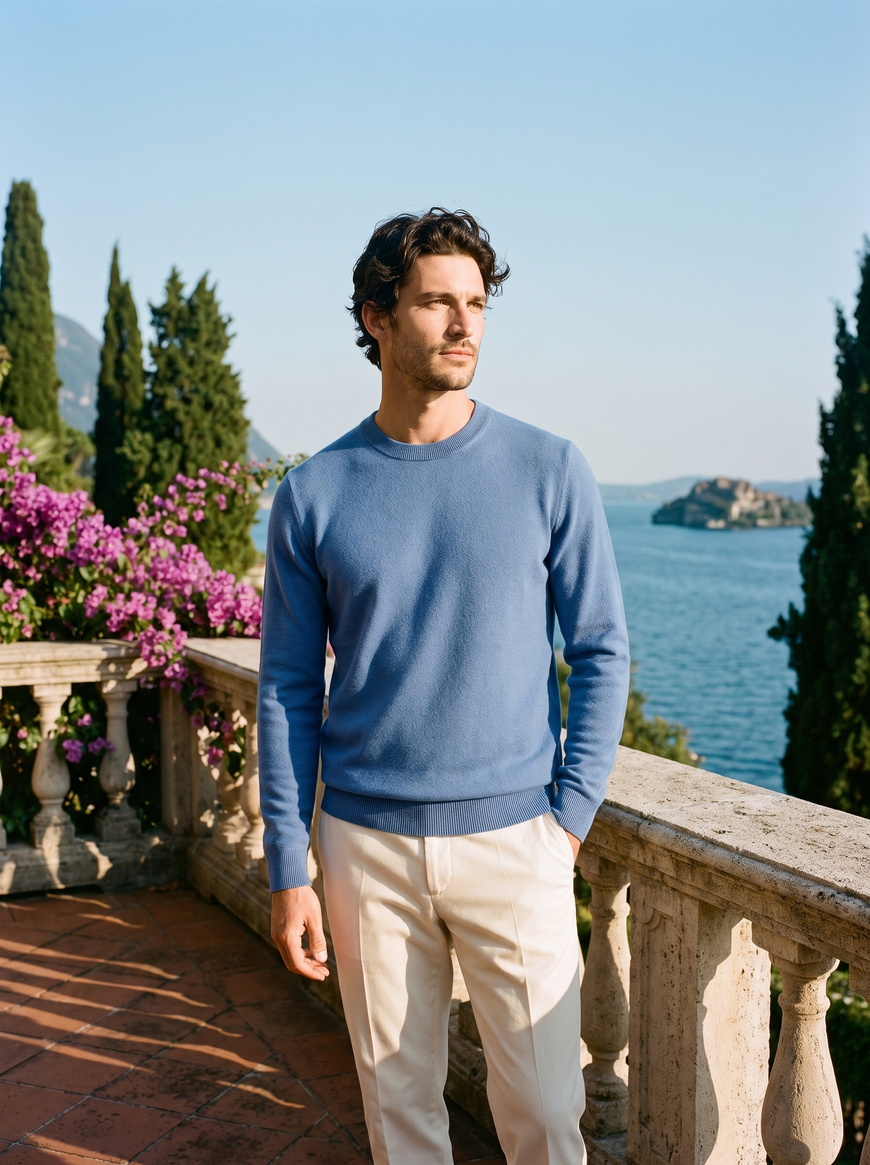Full body view of a man in a blue wool crewneck sweater and cream trousers on a Lake Como terrace — Aveloire