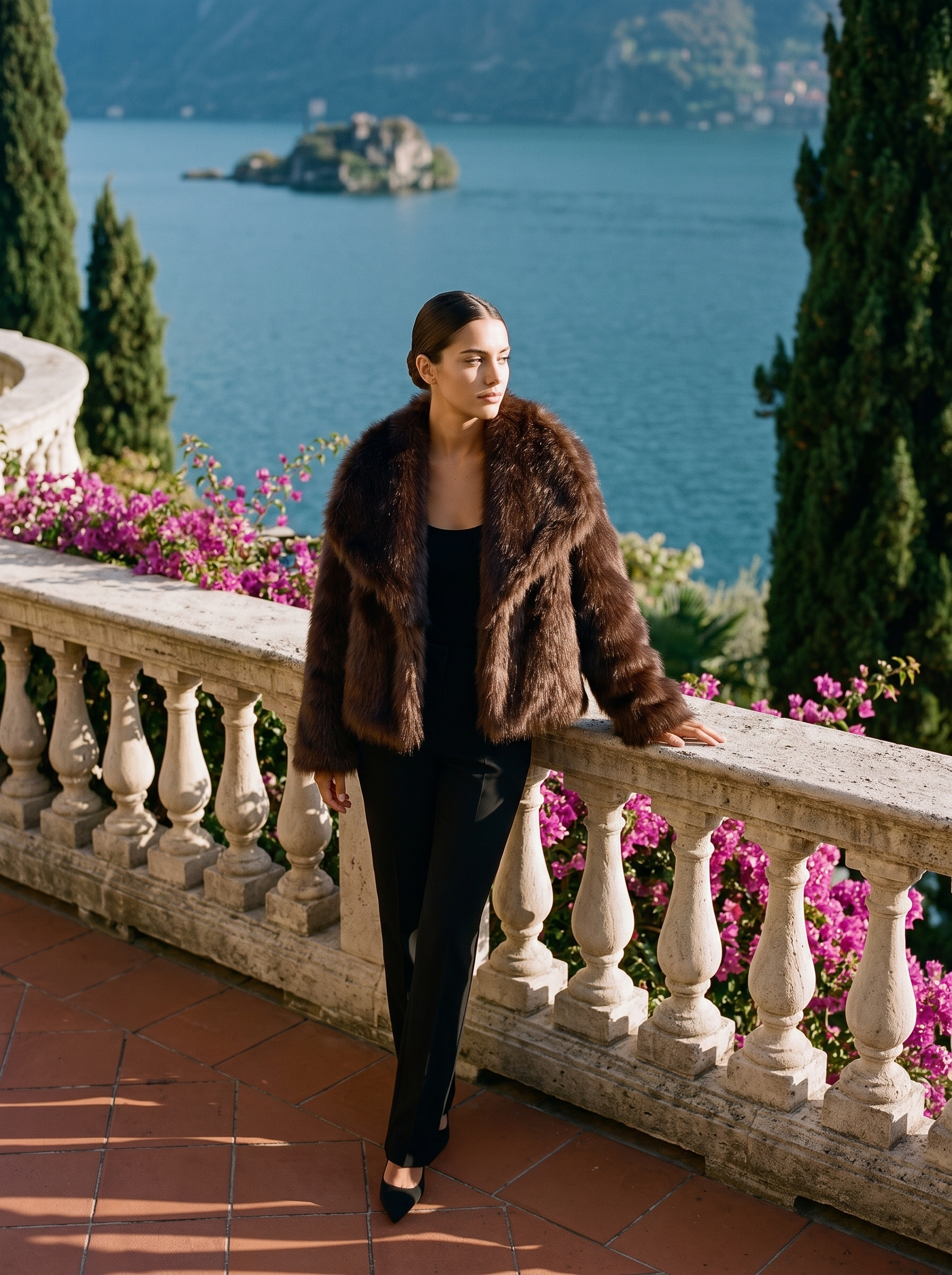 Full-length front view of a brown cropped faux fur coat on a Lake Como terrace — Aveloire