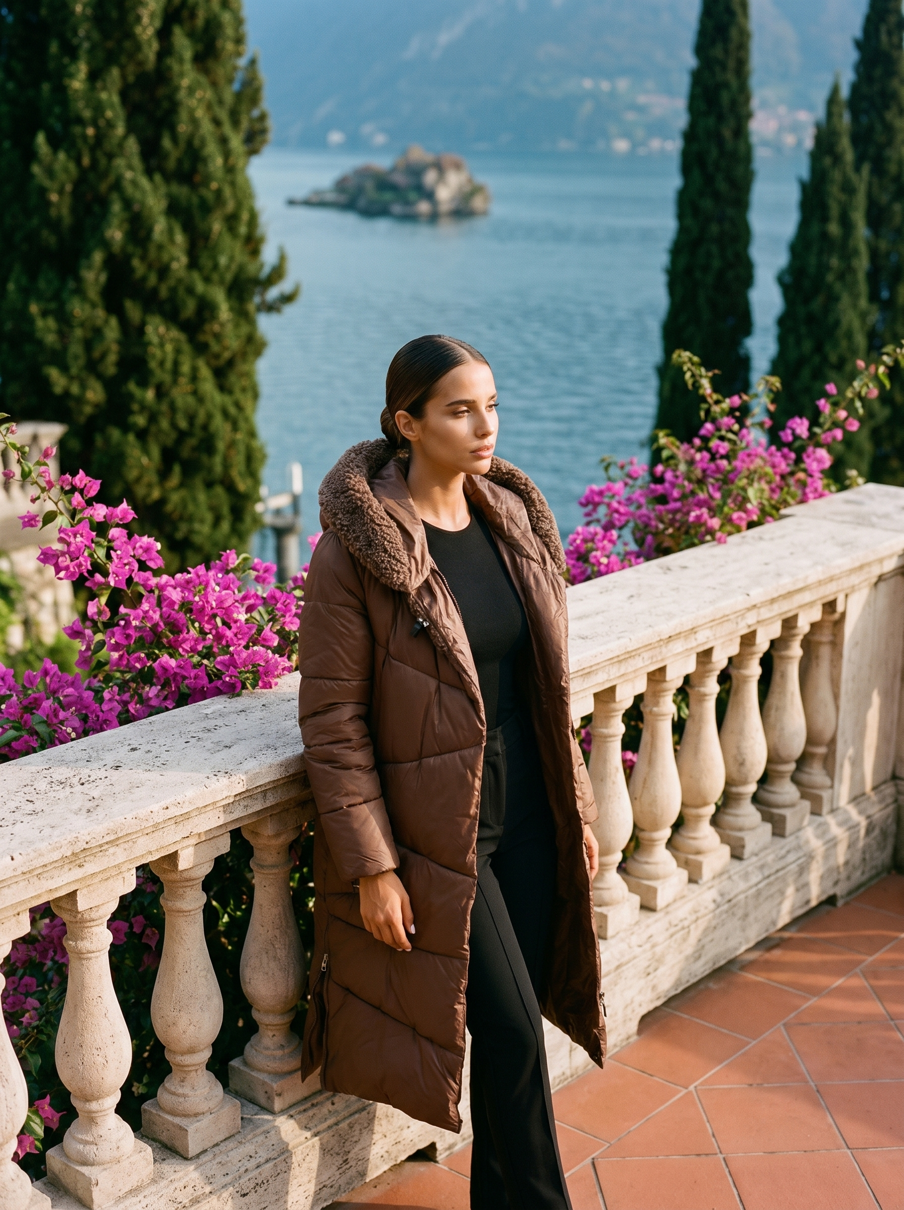 Full-length front view of a brown quilted hooded puffer coat on a Lake Como terrace — Aveloire