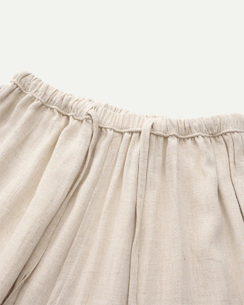 Close-up of beige linen pants with an elastic waistband on a light background