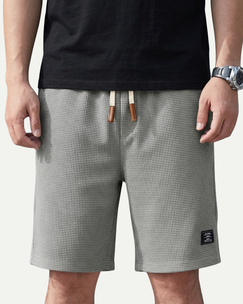 Person wearing gray waffle shorts with a black background