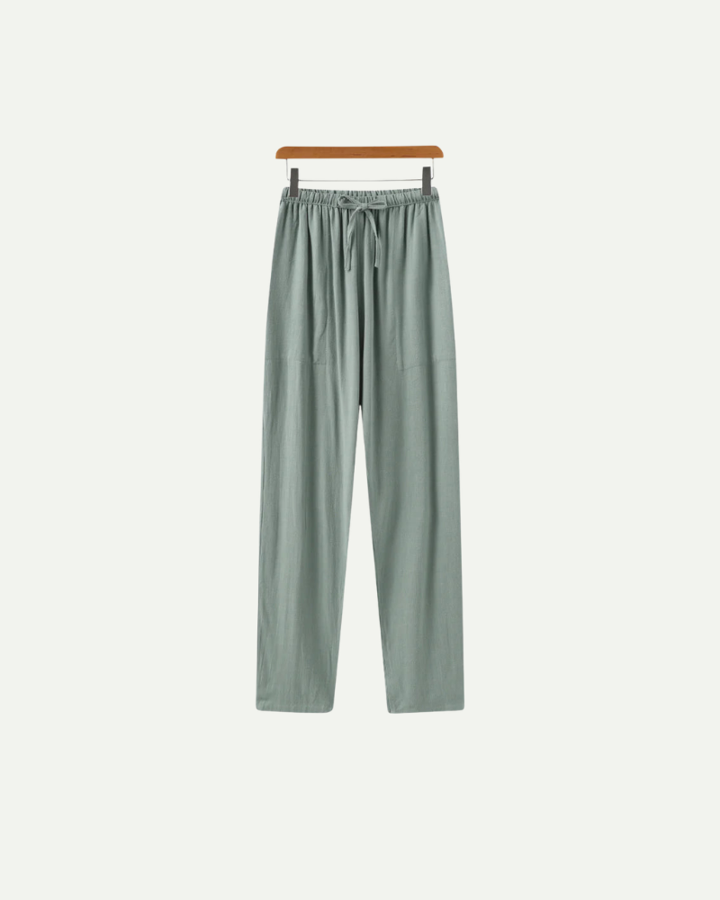 Light green linen pants on a hanger against a white background