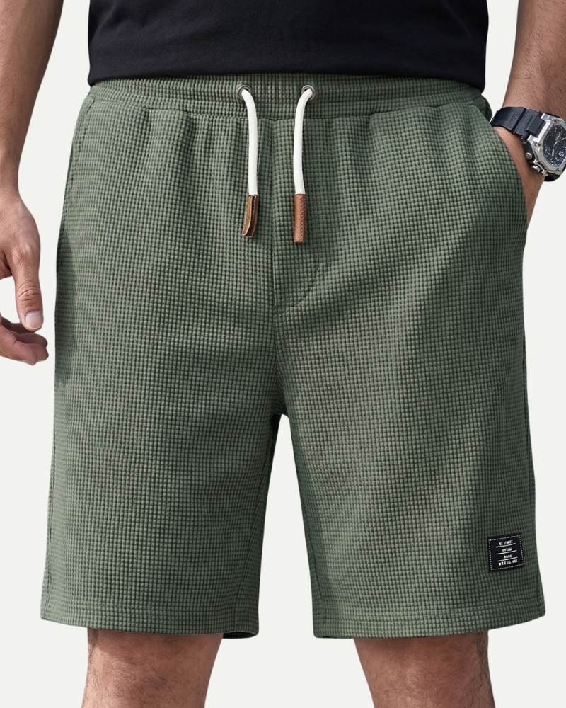 Green waffle shorts with a drawstring on a neutral background