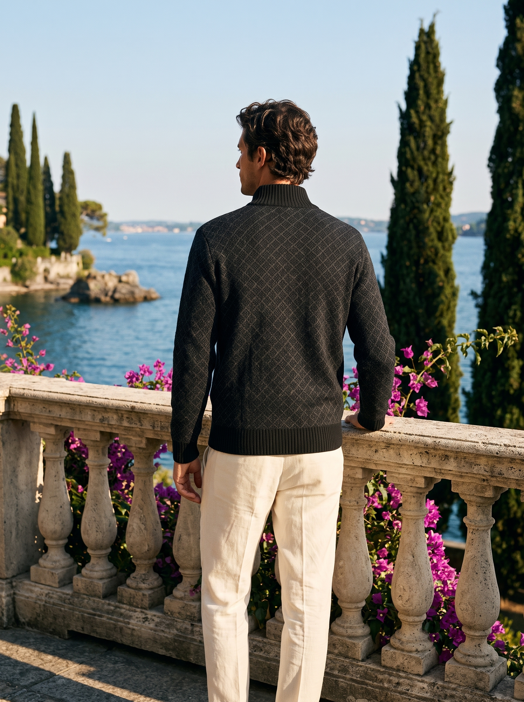 Back view of a black full-zip stand collar cardigan worn on a Mediterranean terrace — Aveloire