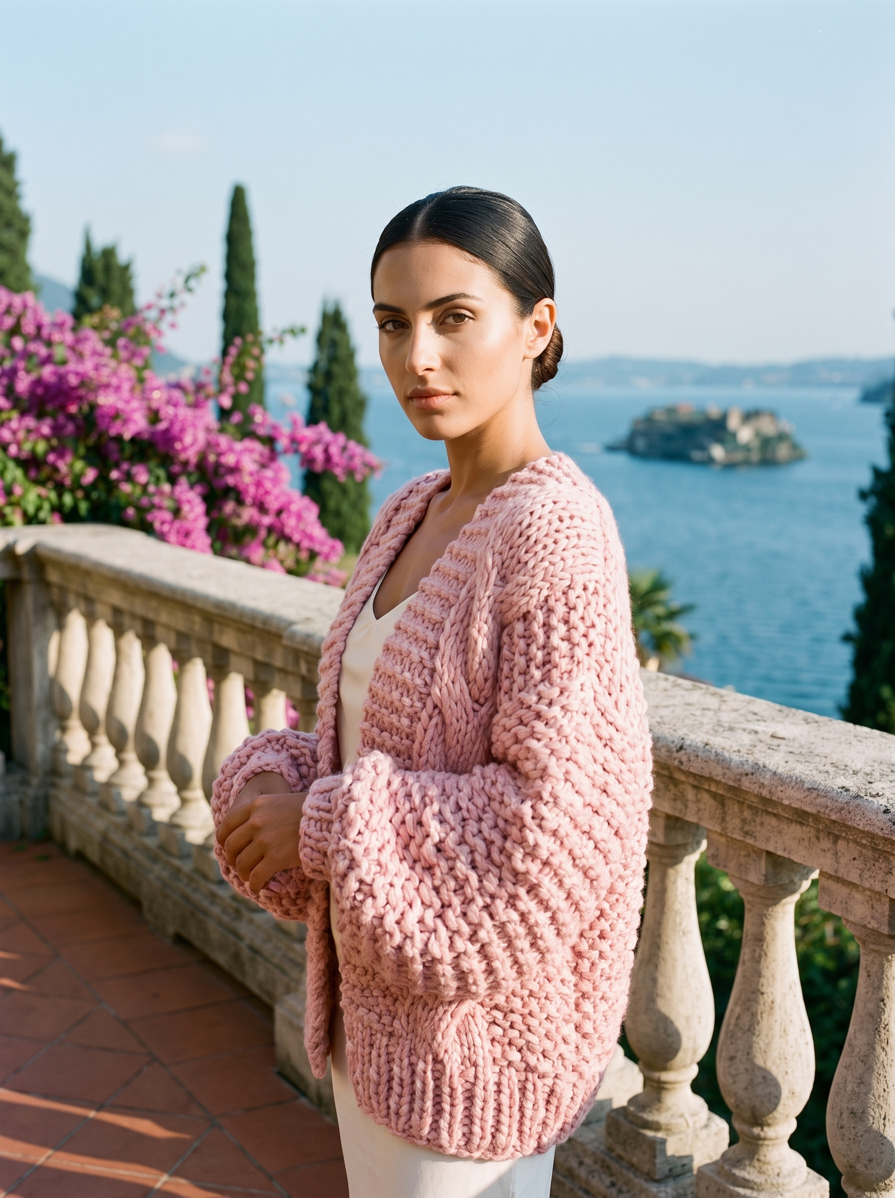 Woman wearing a blush pink chunky knit open-front cardigan on a Lake Como terrace — Aveloire