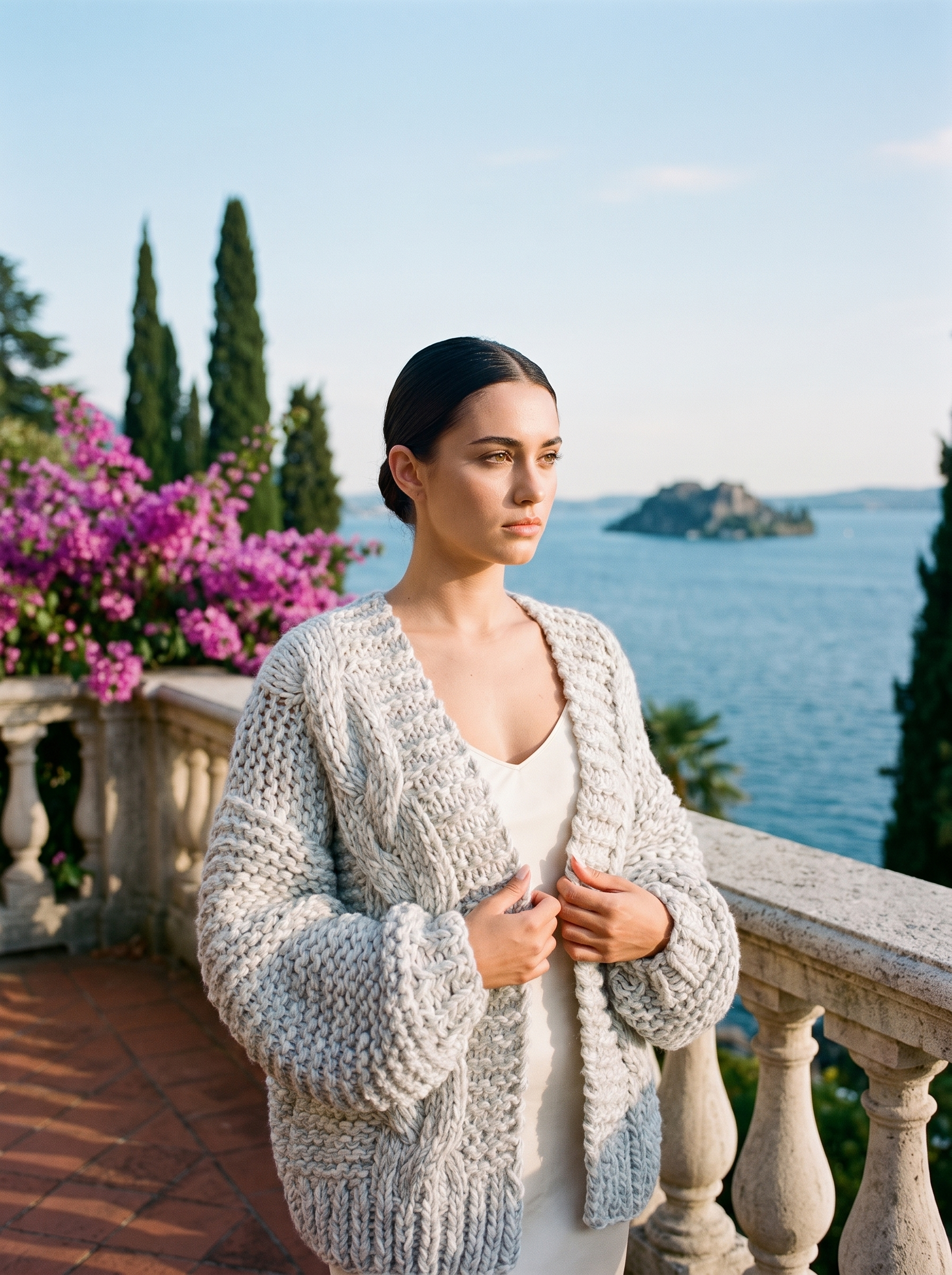 Woman wearing a heathered light grey chunky knit open-front cardigan on a Lake Como terrace — Aveloire