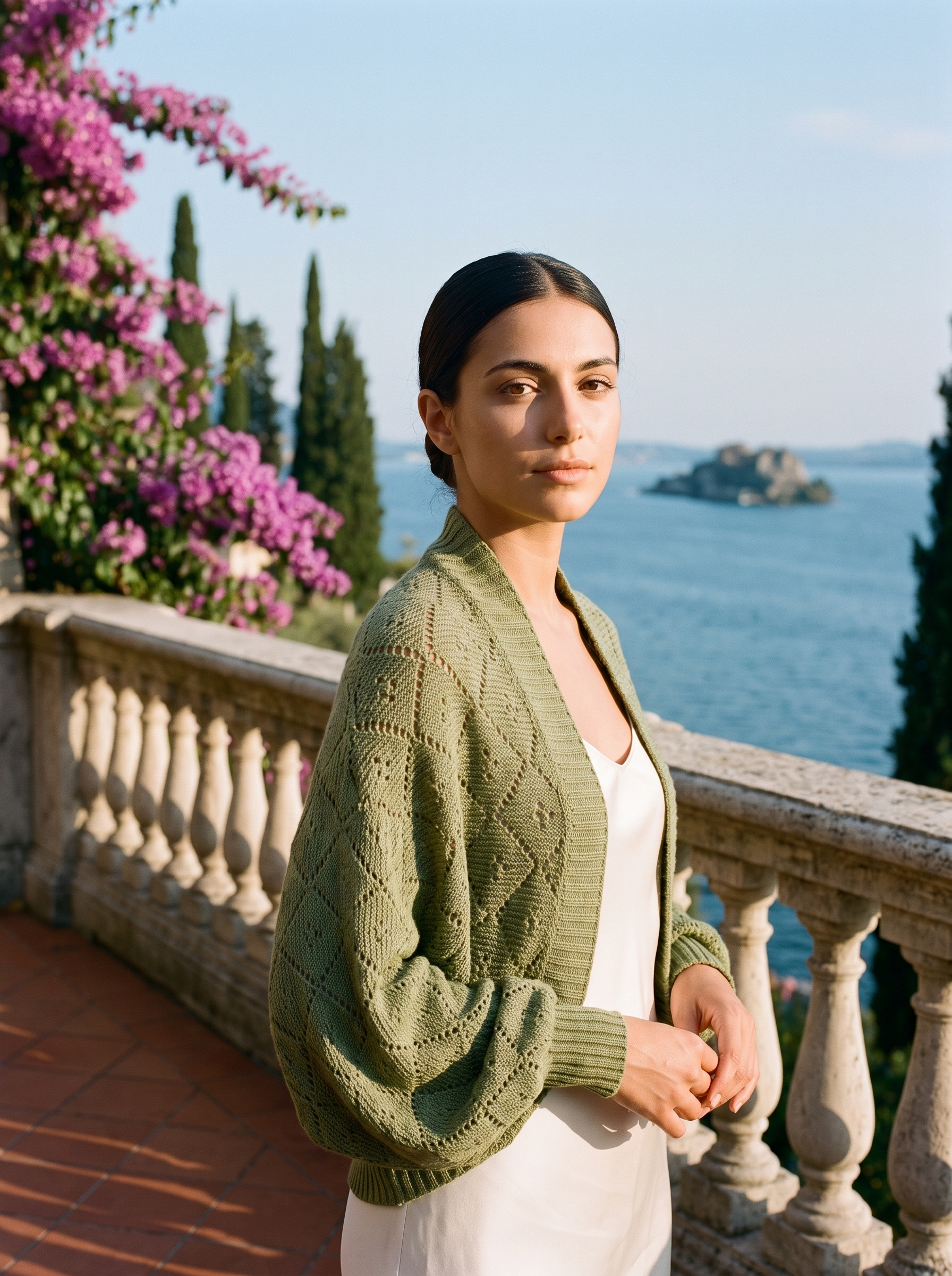 Woman wearing a sage olive cropped open-front knit shrug cardigan on a Lake Como terrace — Aveloire