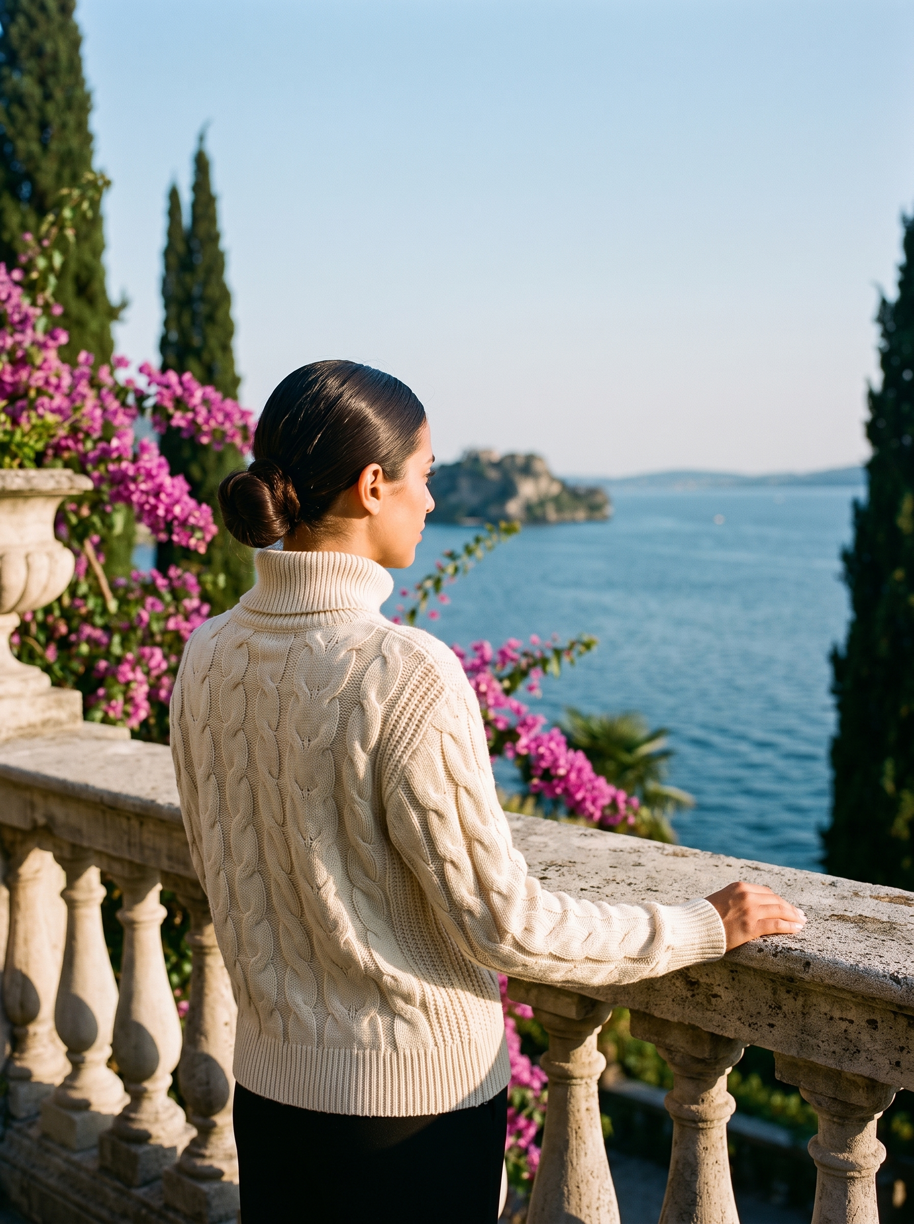 Back view of a cream cable-knit turtleneck sweater on a Lake Como terrace — Aveloire