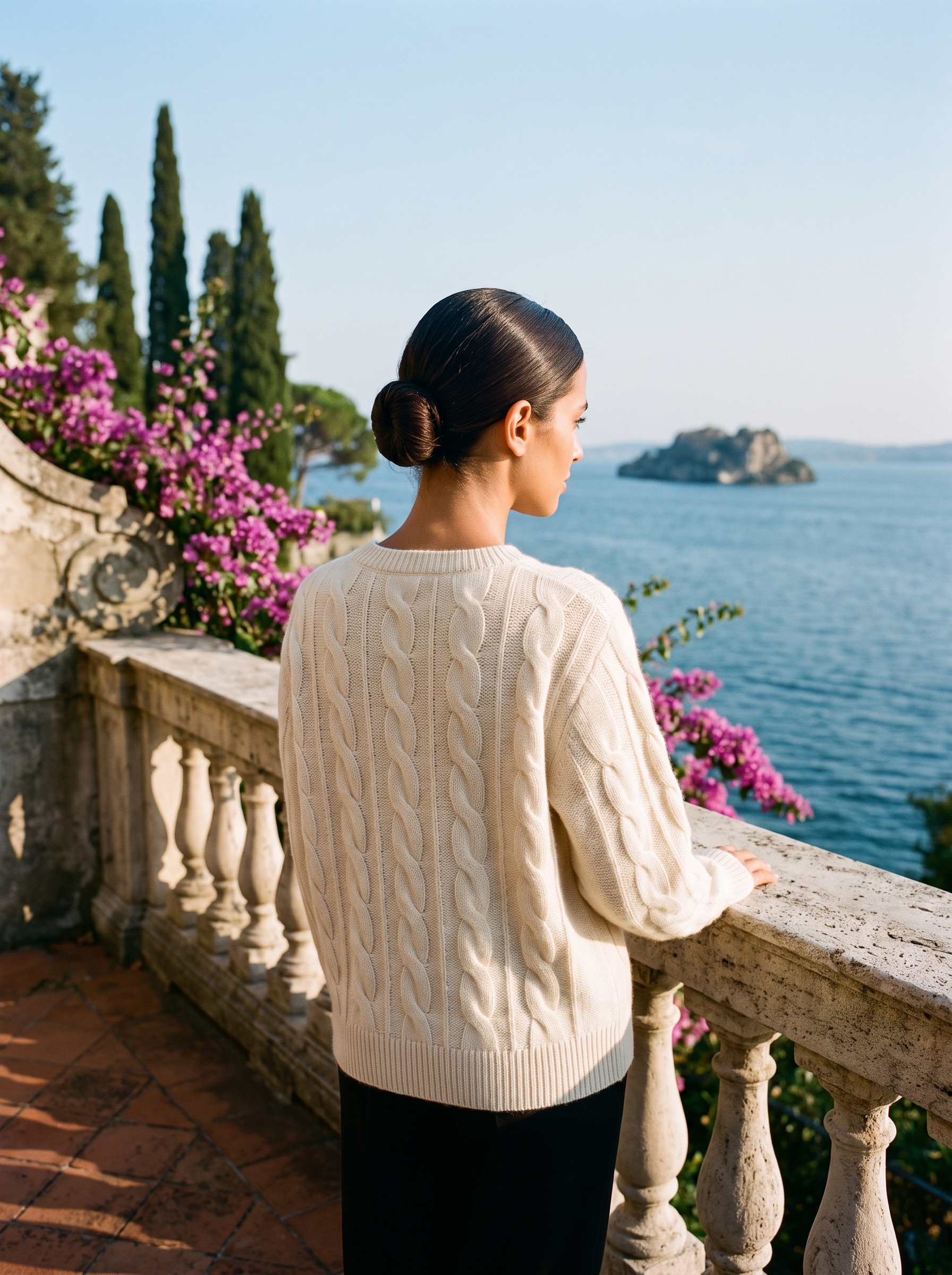 Back view of a cream cable-knit crew neck sweater on a Lake Como terrace — Aveloire