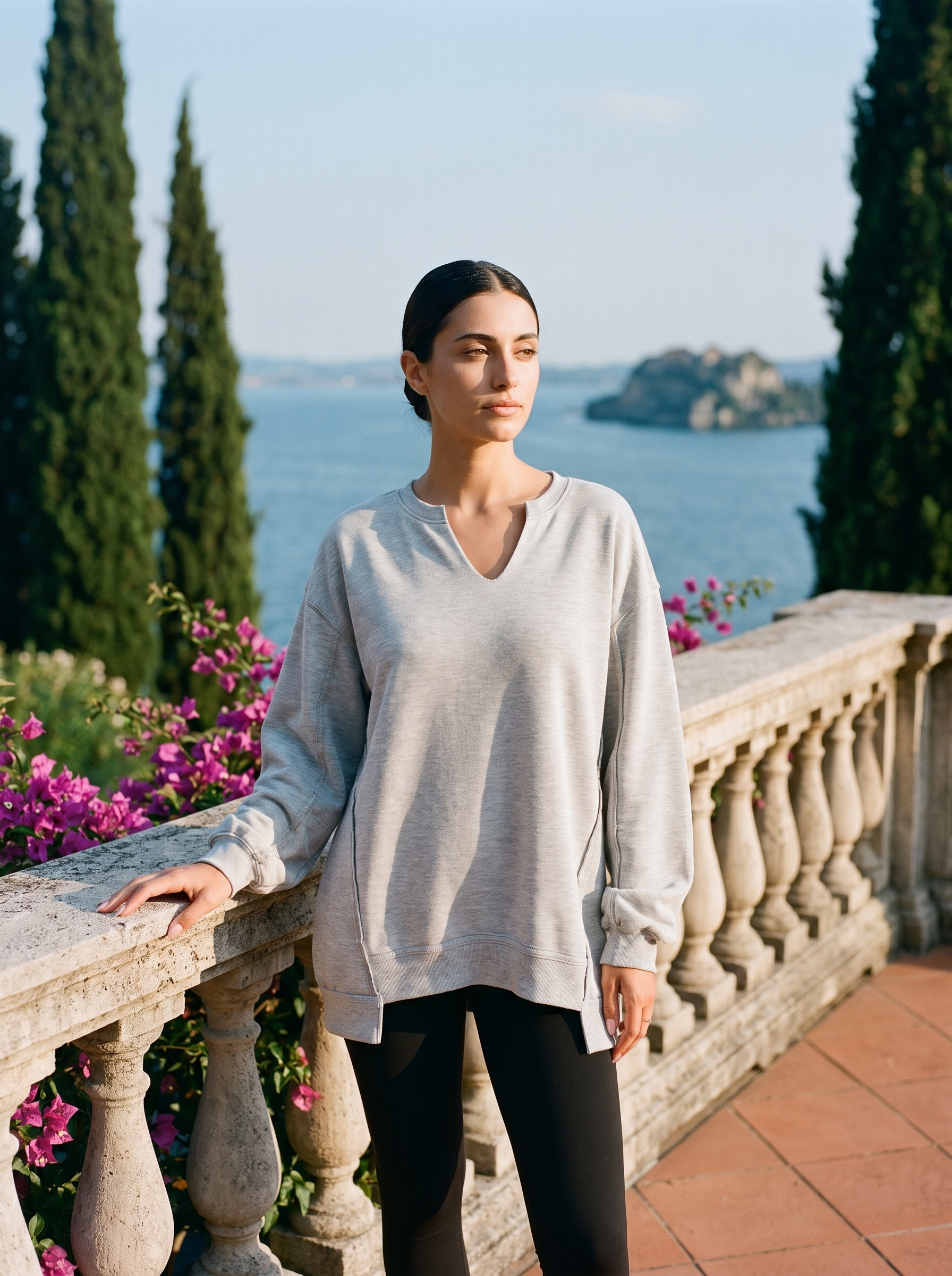 Woman wearing a light grey V-neck sweatshirt tunic on a Lake Como terrace, old money style — Aveloire