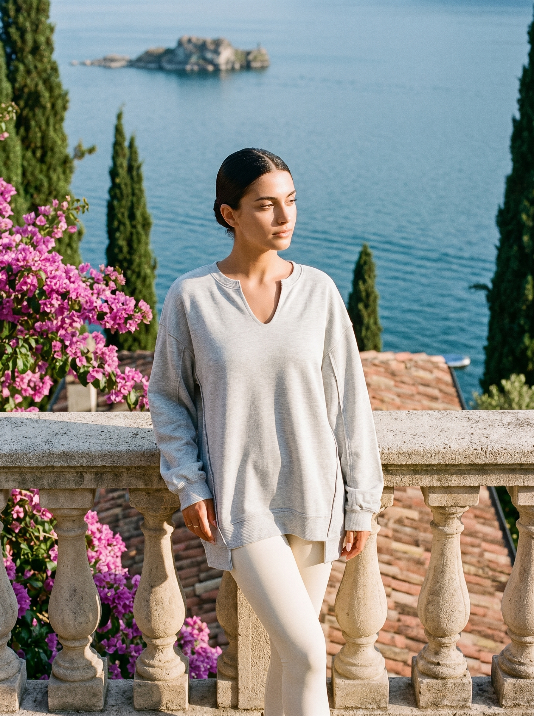 Woman wearing a light grey V-neck sweatshirt tunic full length on a Lake Como terrace, old money style — Aveloire