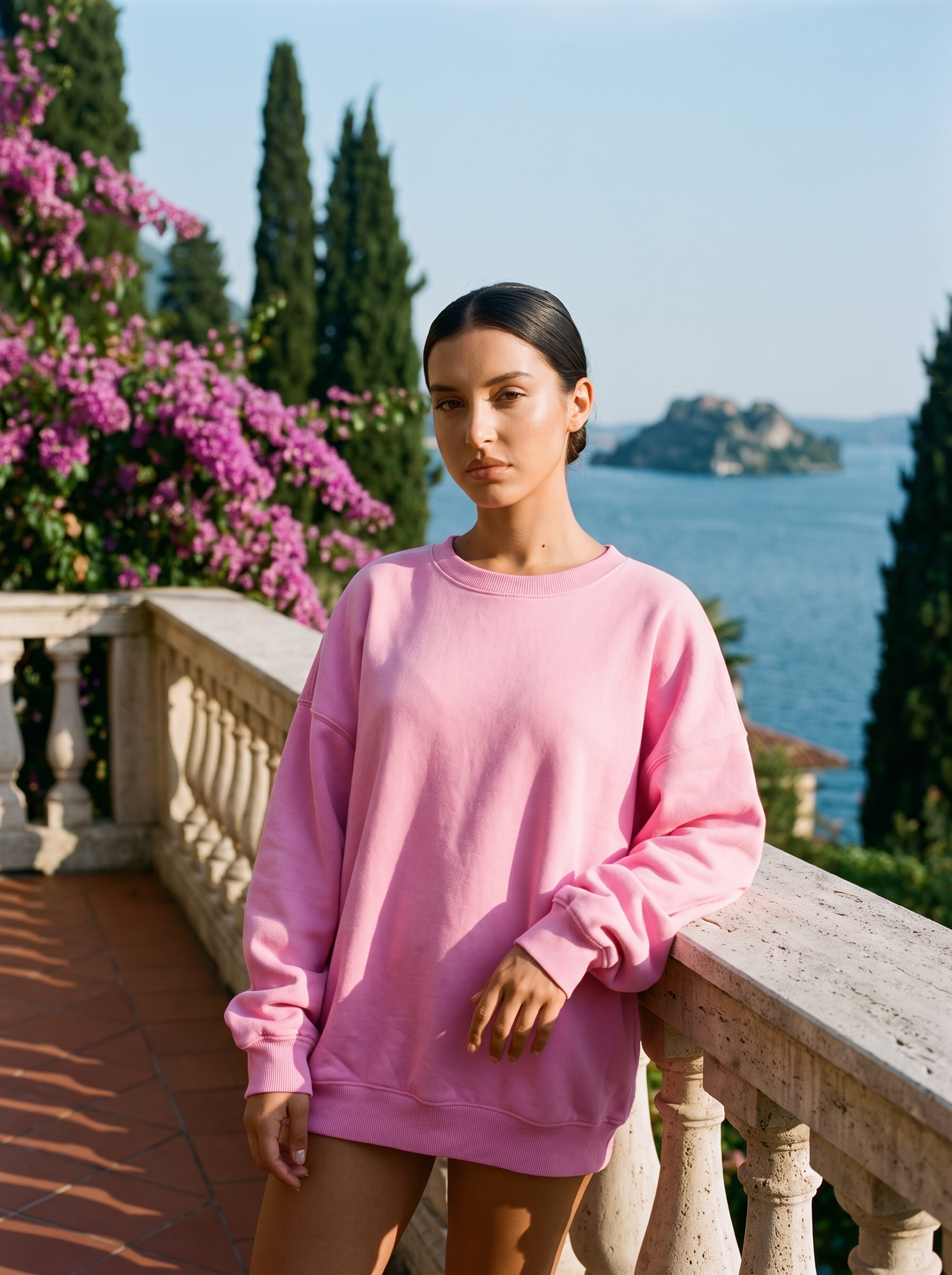 Woman wearing a candy pink oversized crew neck sweatshirt on a Lake Como terrace, old money style — Aveloire