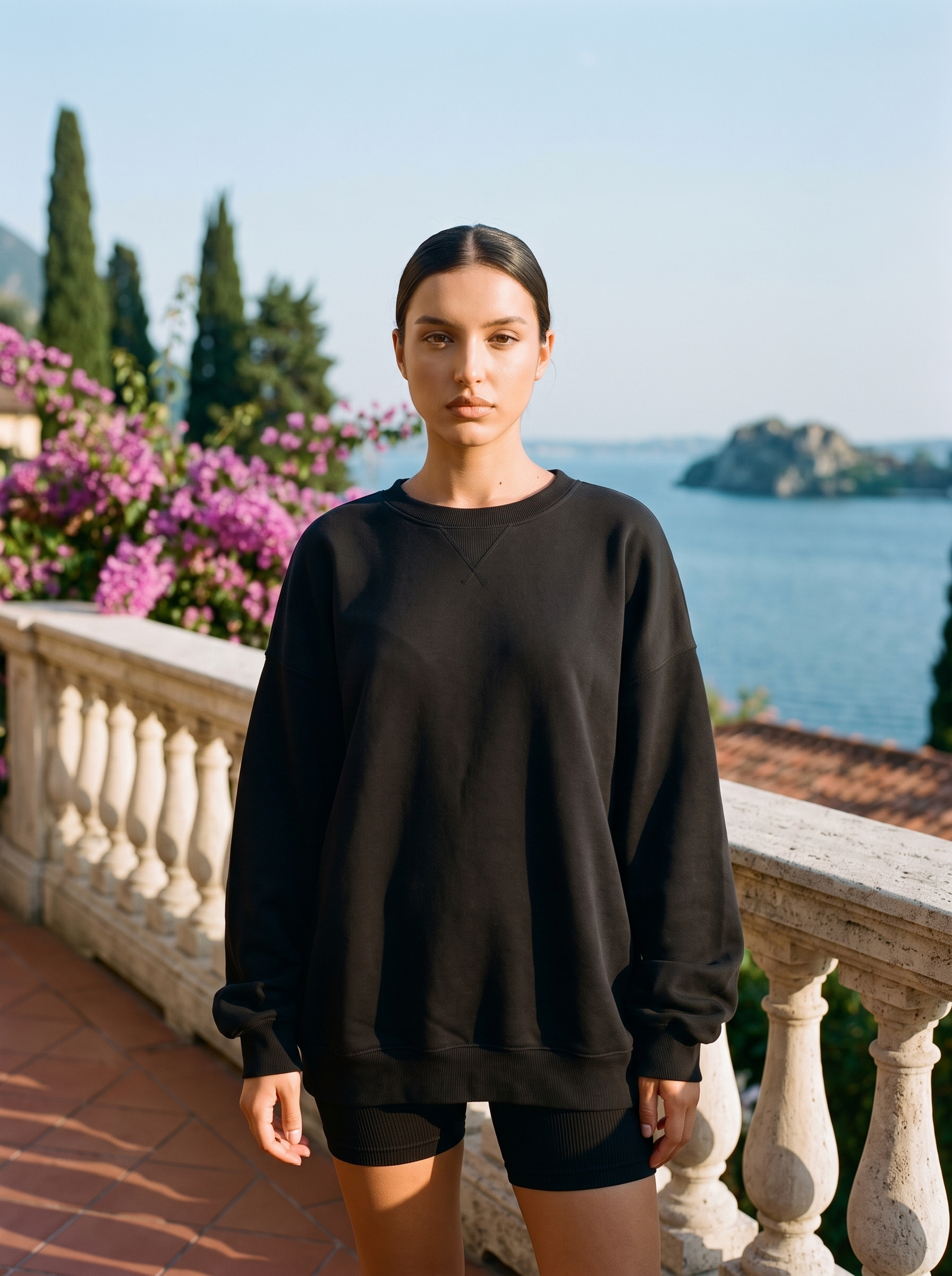 Woman wearing a black oversized crew neck sweatshirt on a Lake Como terrace, old money style — Aveloire