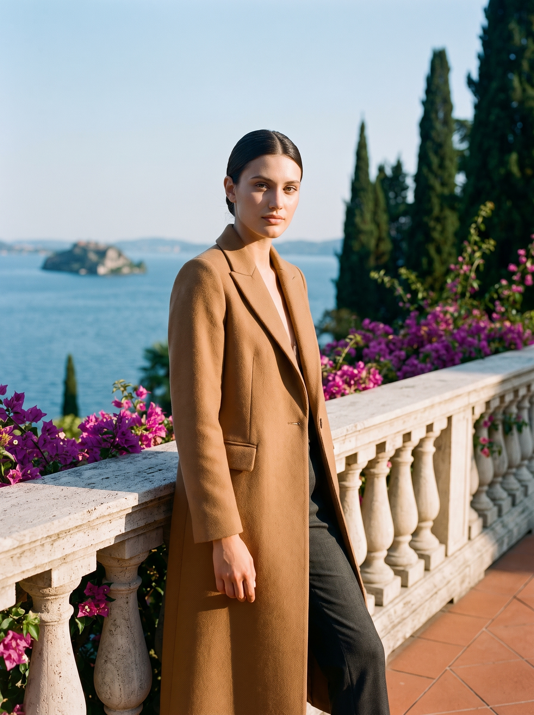 Woman wearing a camel brown single-button longline wool coat on a Lake Como terrace, old money style — Aveloire