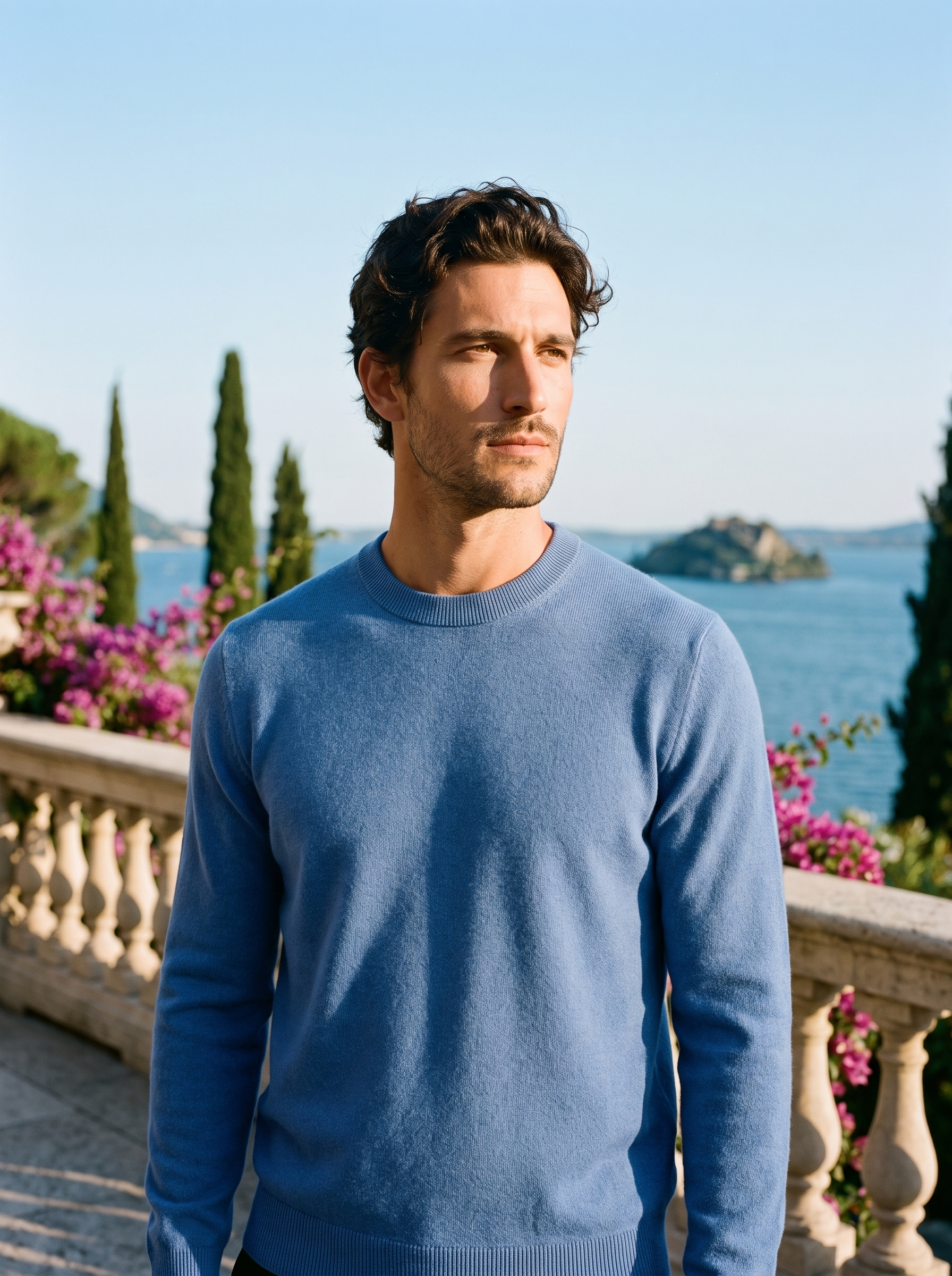 Man wearing a blue 100% wool crewneck sweater on a terrace overlooking Lake Como, old money style — Aveloire