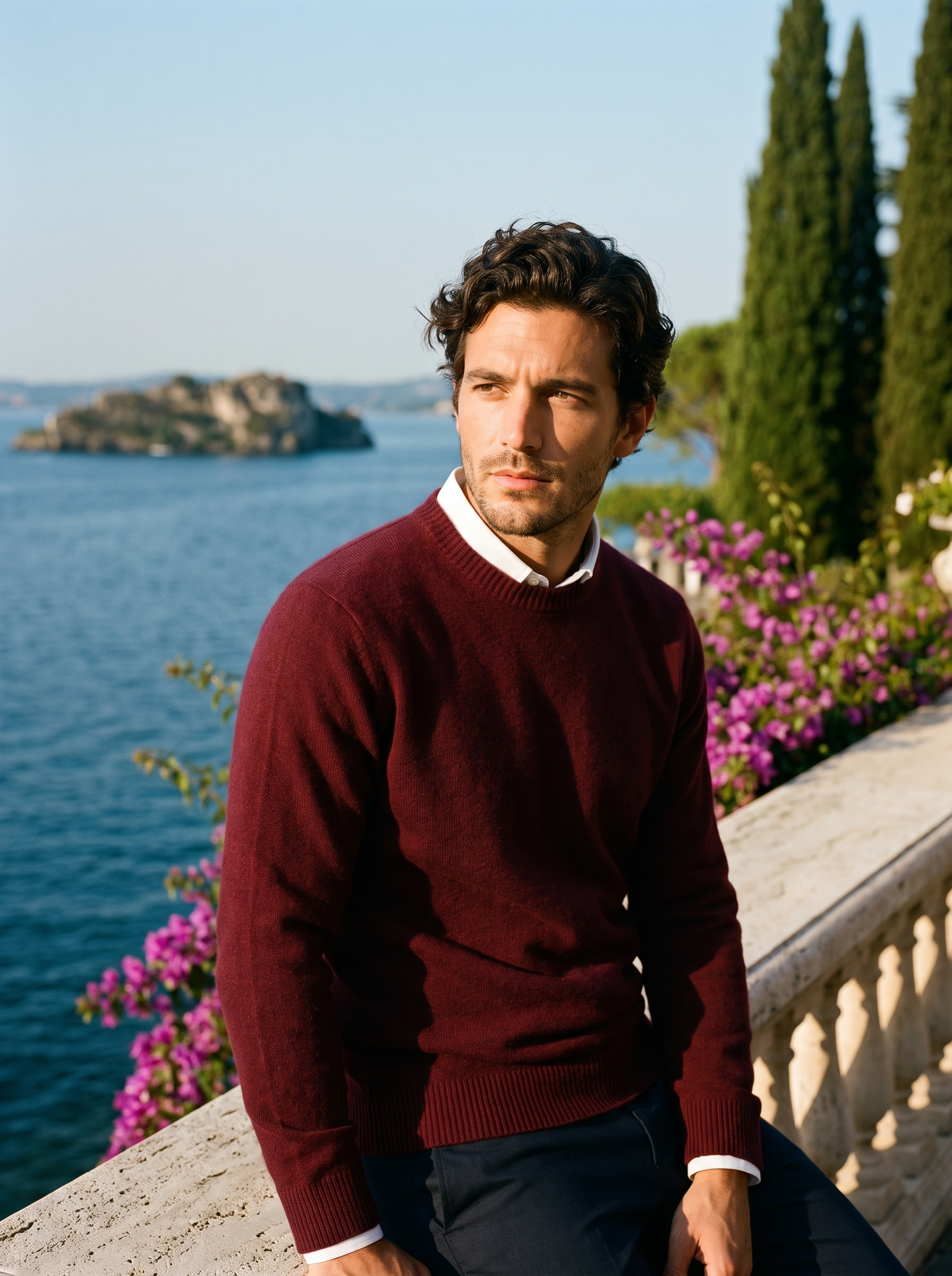 Man wearing a burgundy classic crewneck sweater on a terrace overlooking Lake Como, old money style — Aveloire
