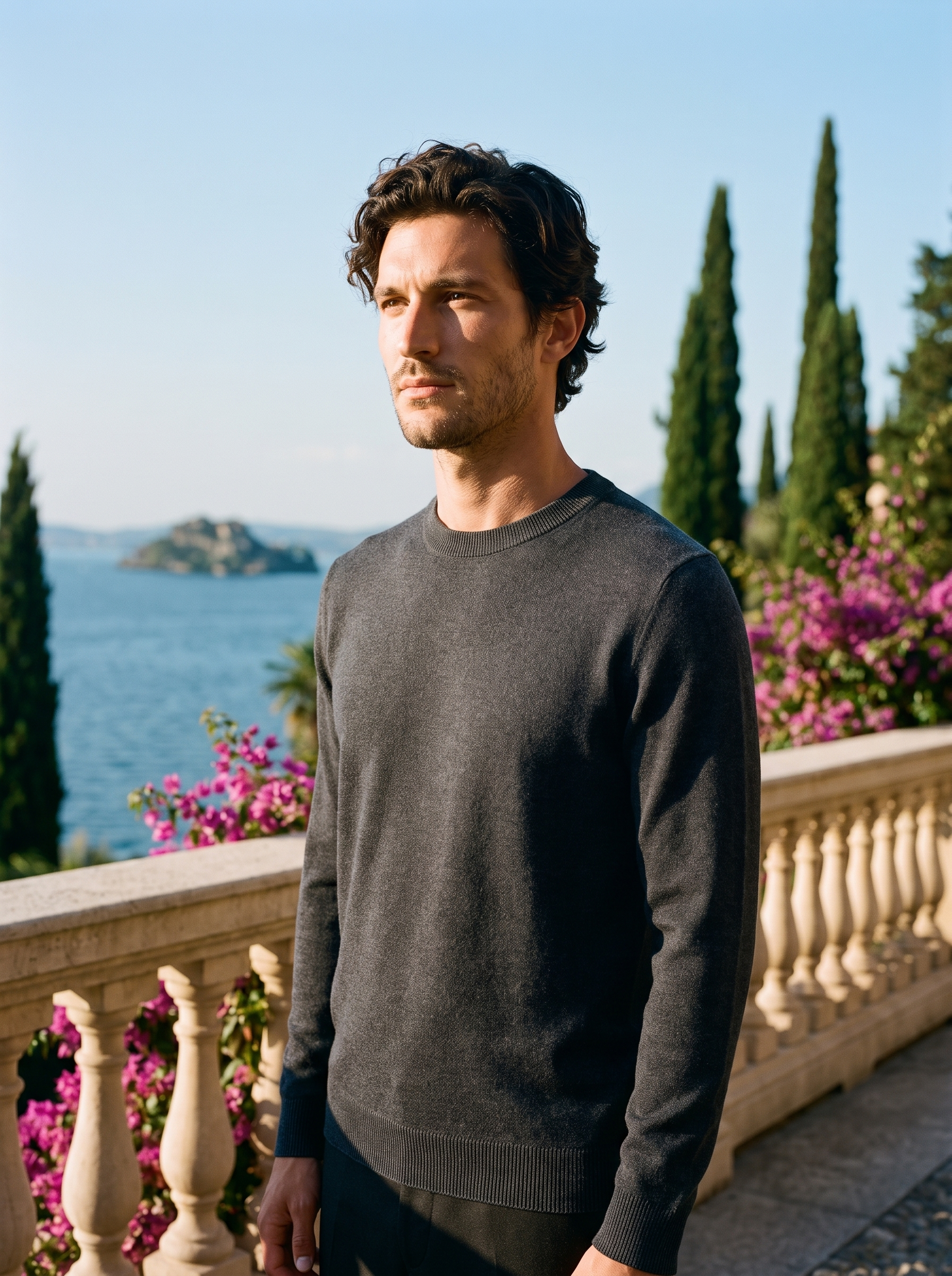 Man wearing a dark gray 100% wool crewneck sweater on a terrace overlooking Lake Como, old money style — Aveloire