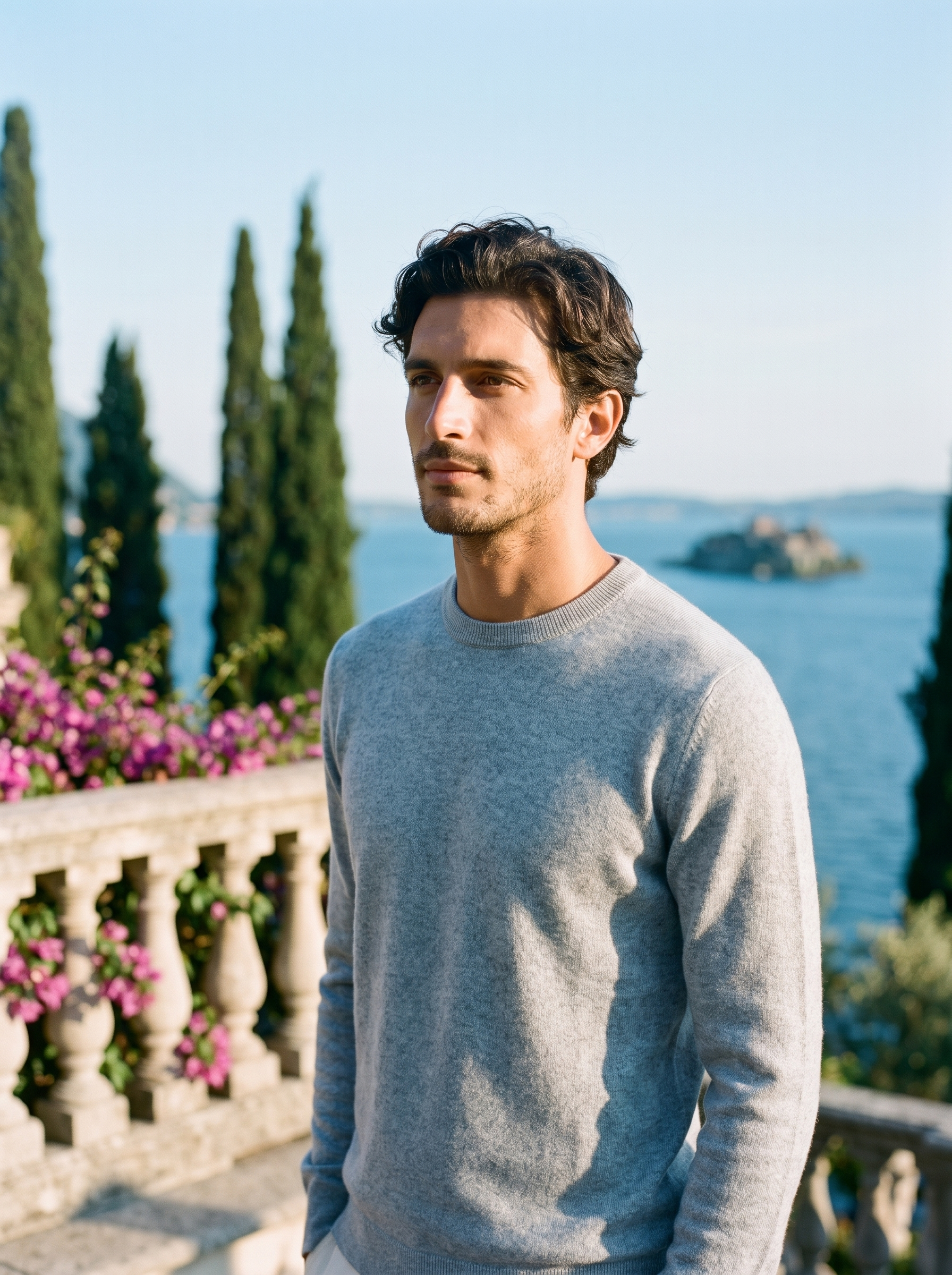 Man wearing a misty blue crewneck sweater on a terrace overlooking Lake Como, old money style — Aveloire