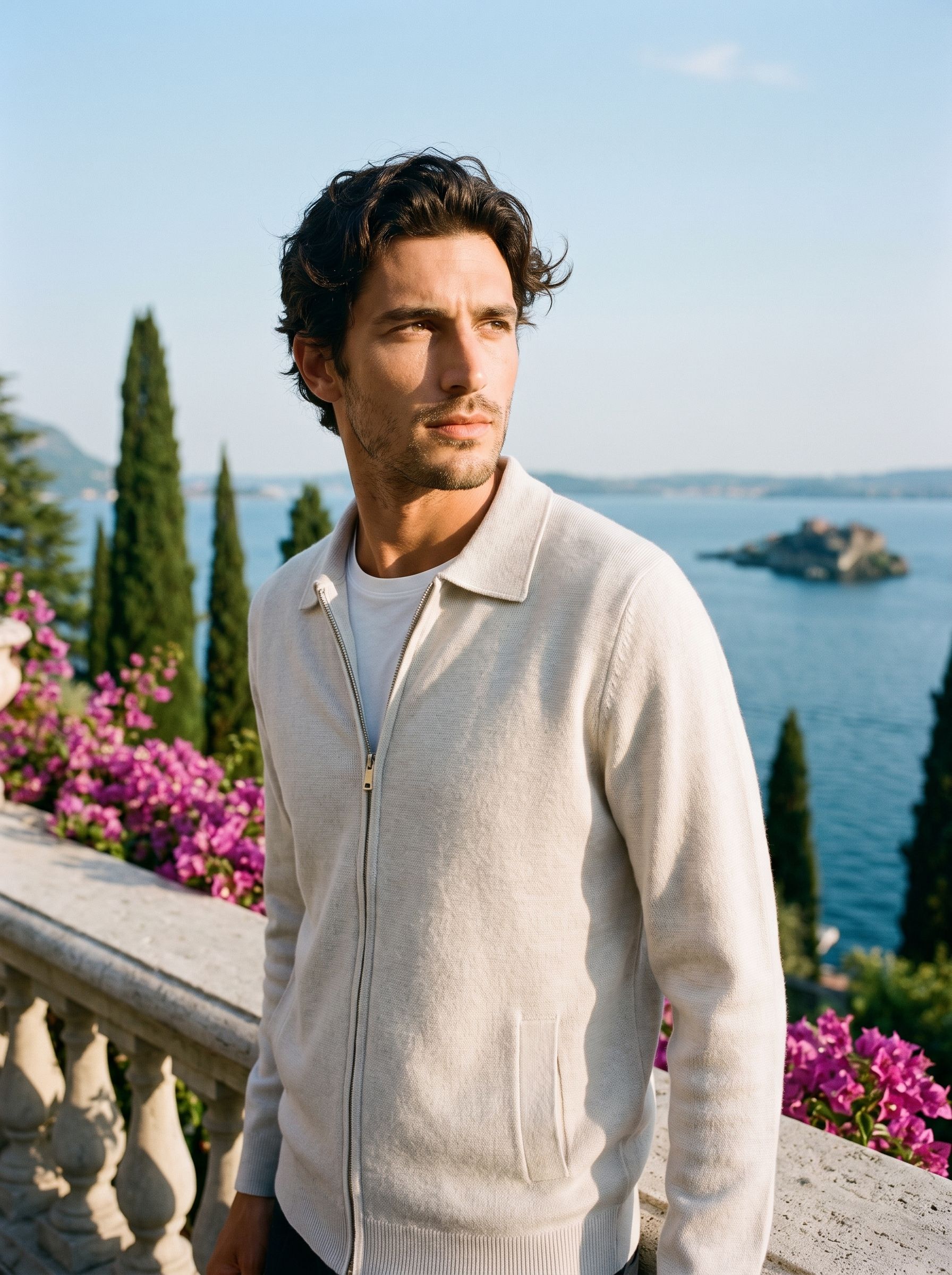Man wearing a white mercerized wool zip-up collared cardigan on a terrace overlooking Lake Como, old money style — Aveloire