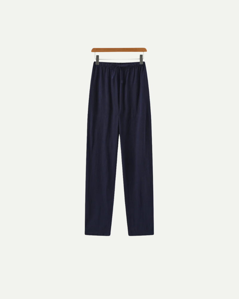 Navy blue linen pants hanging on a wooden hanger against a white background