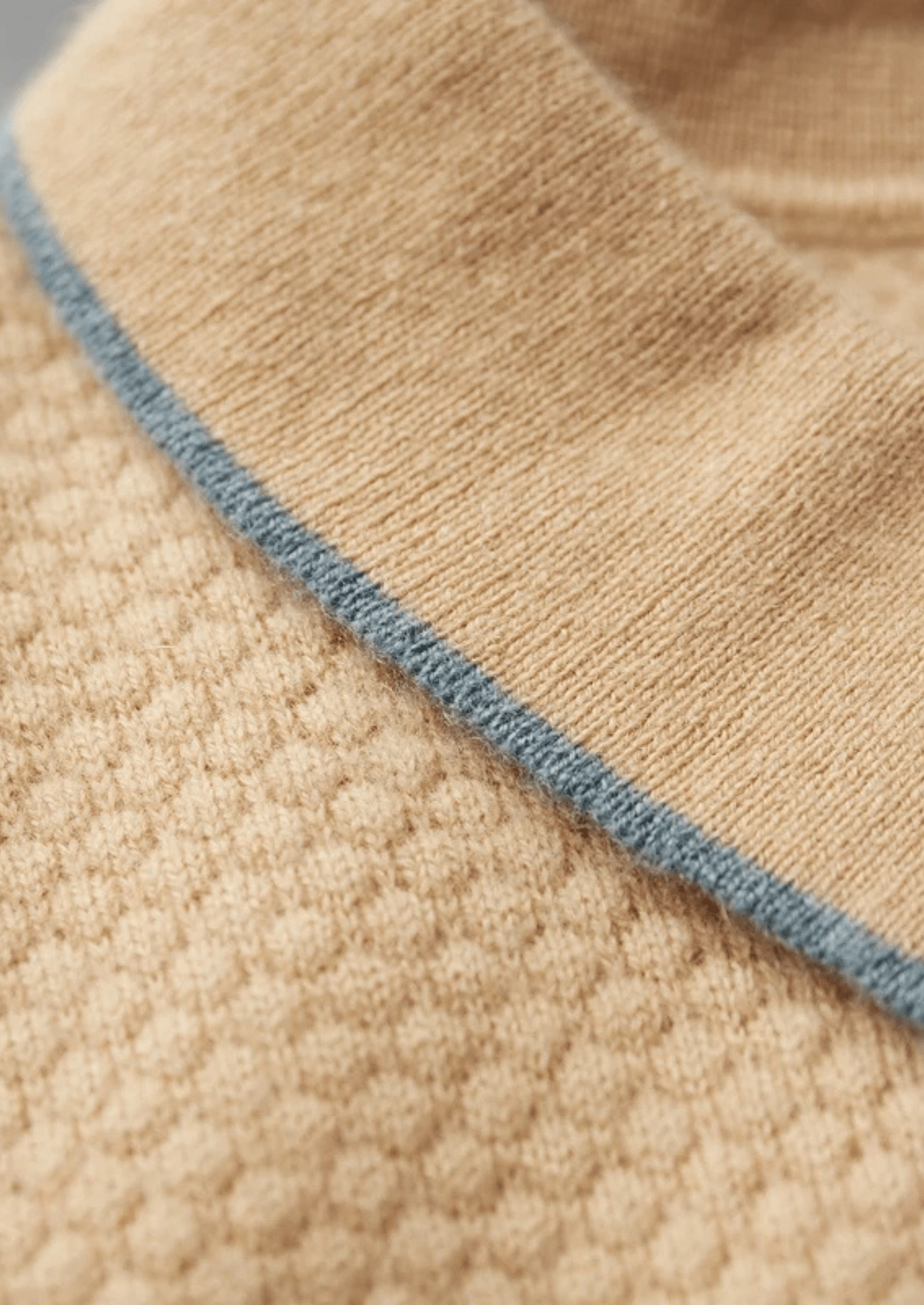 Close-up of beige fabric with blue stitching detail