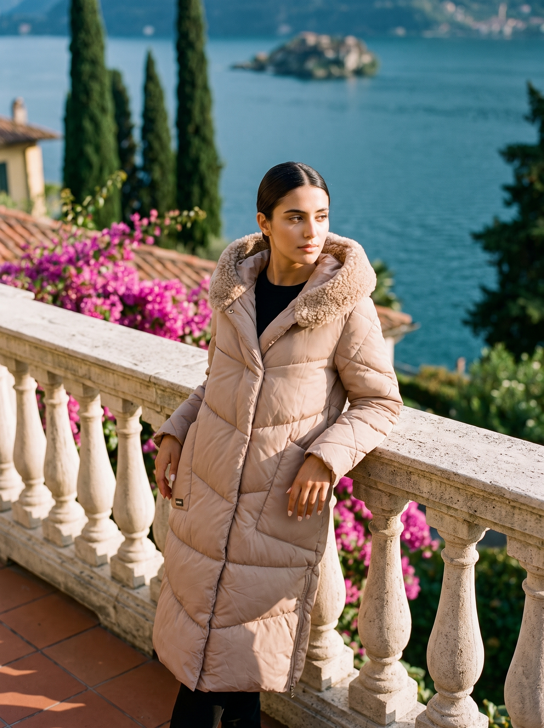 Woman wearing a latte-beige quilted hooded puffer coat on a Lake Como terrace — Aveloire