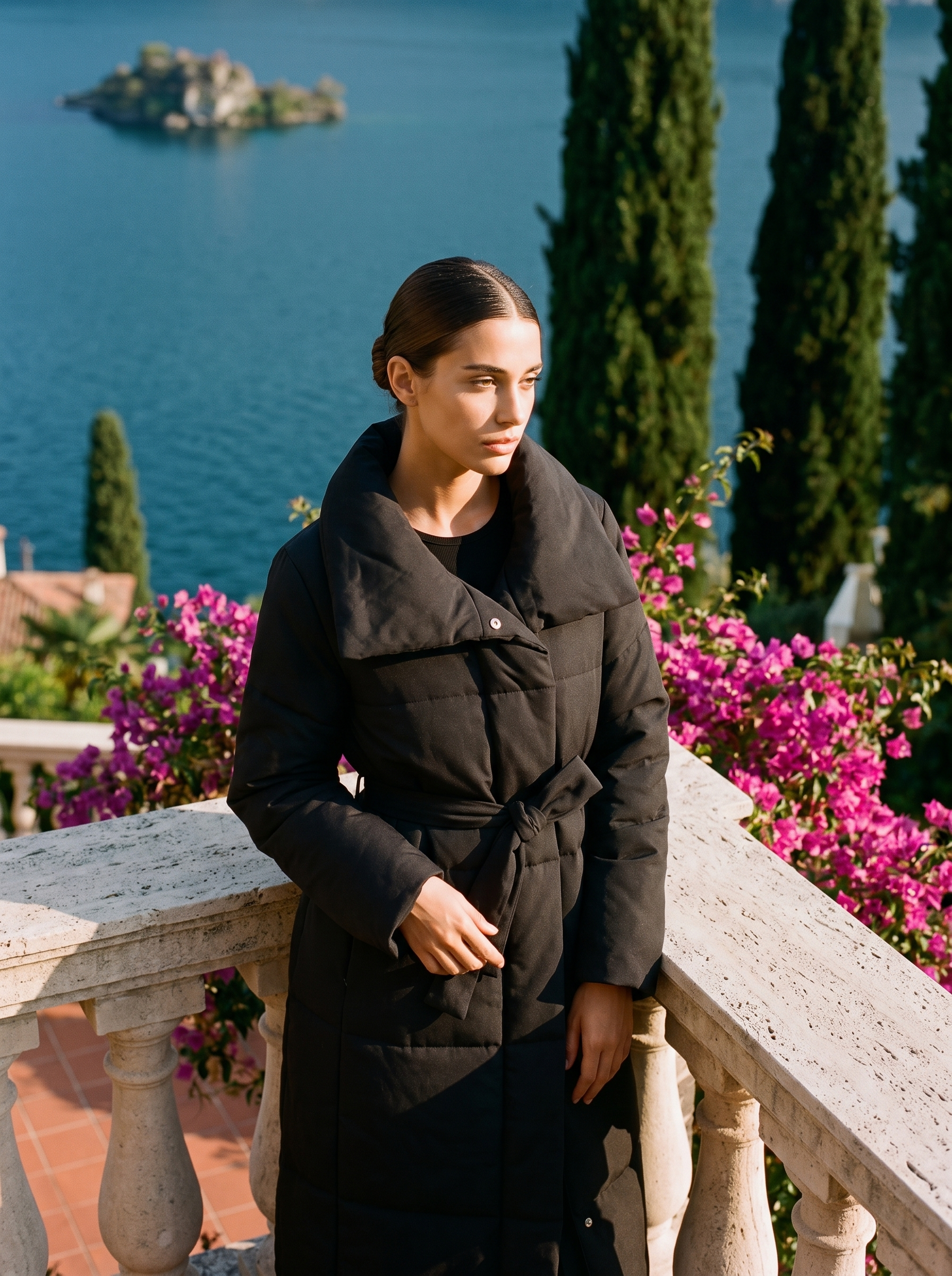 Woman wearing a black belted quilted coat on a Lake Como terrace — Aveloire