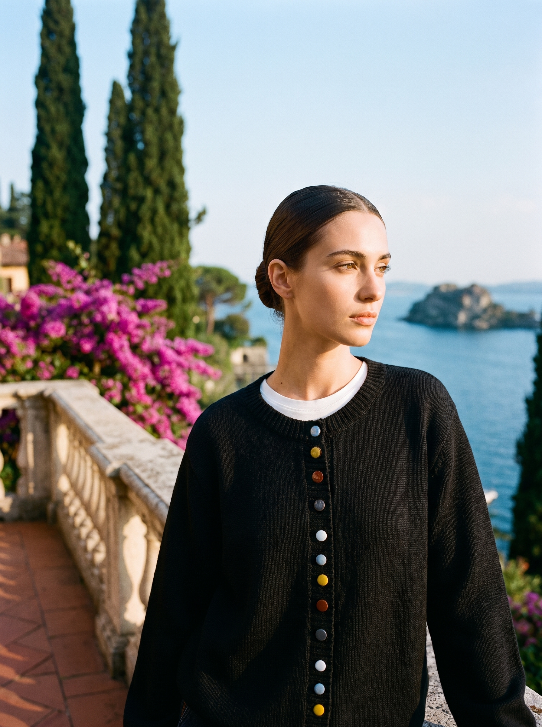Woman wearing a black button cardigan on a terrace overlooking Lake Como, old money style — Aveloire