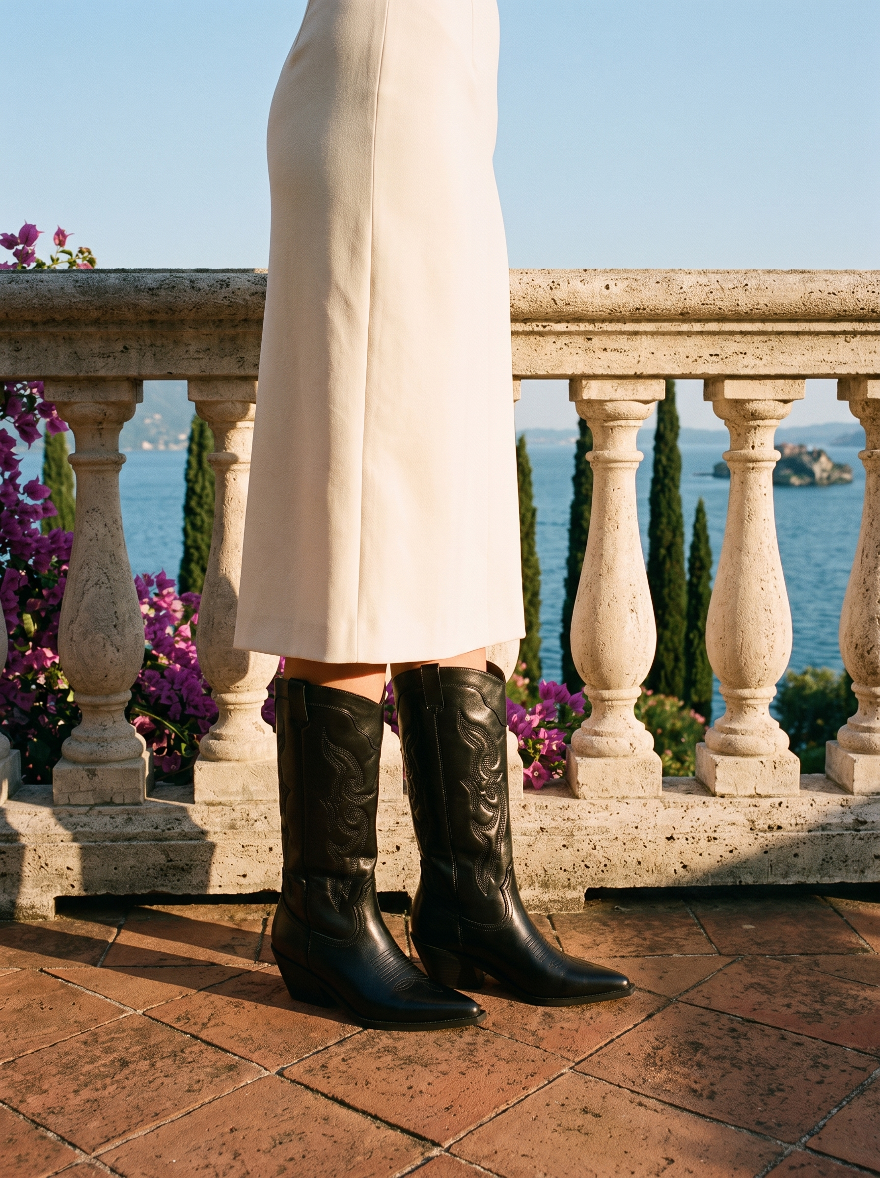 Woman wearing black pointed toe western knee high boots on a terrace overlooking Lake Como, old money style — Aveloire