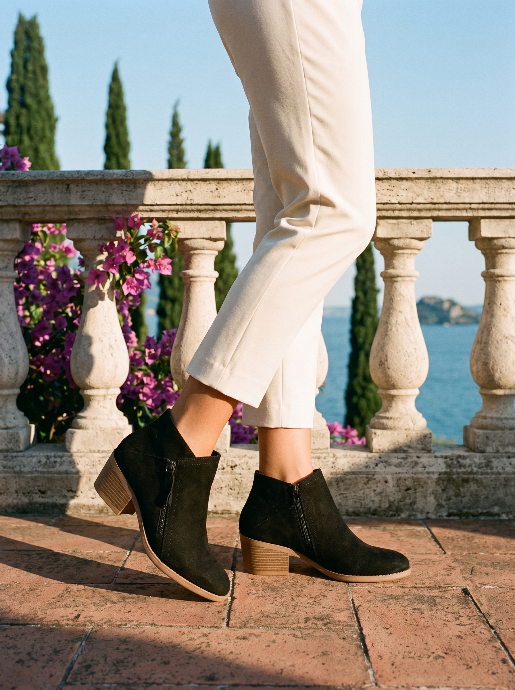 Woman wearing black suede side zip ankle boots on a terrace overlooking Lake Como, old money style — Aveloire