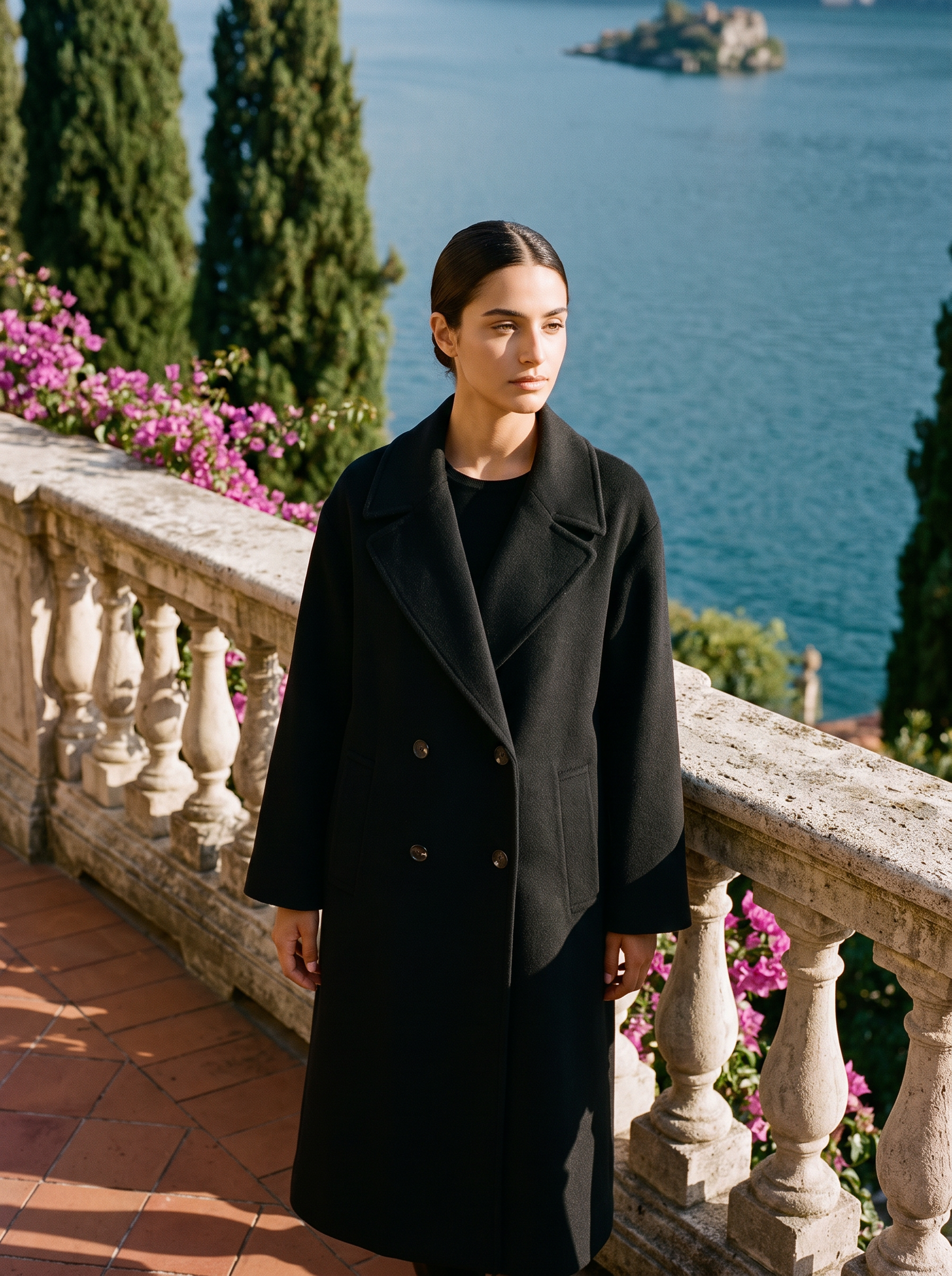 Woman wearing a black double-breasted wool overcoat on a Lake Como terrace — Aveloire