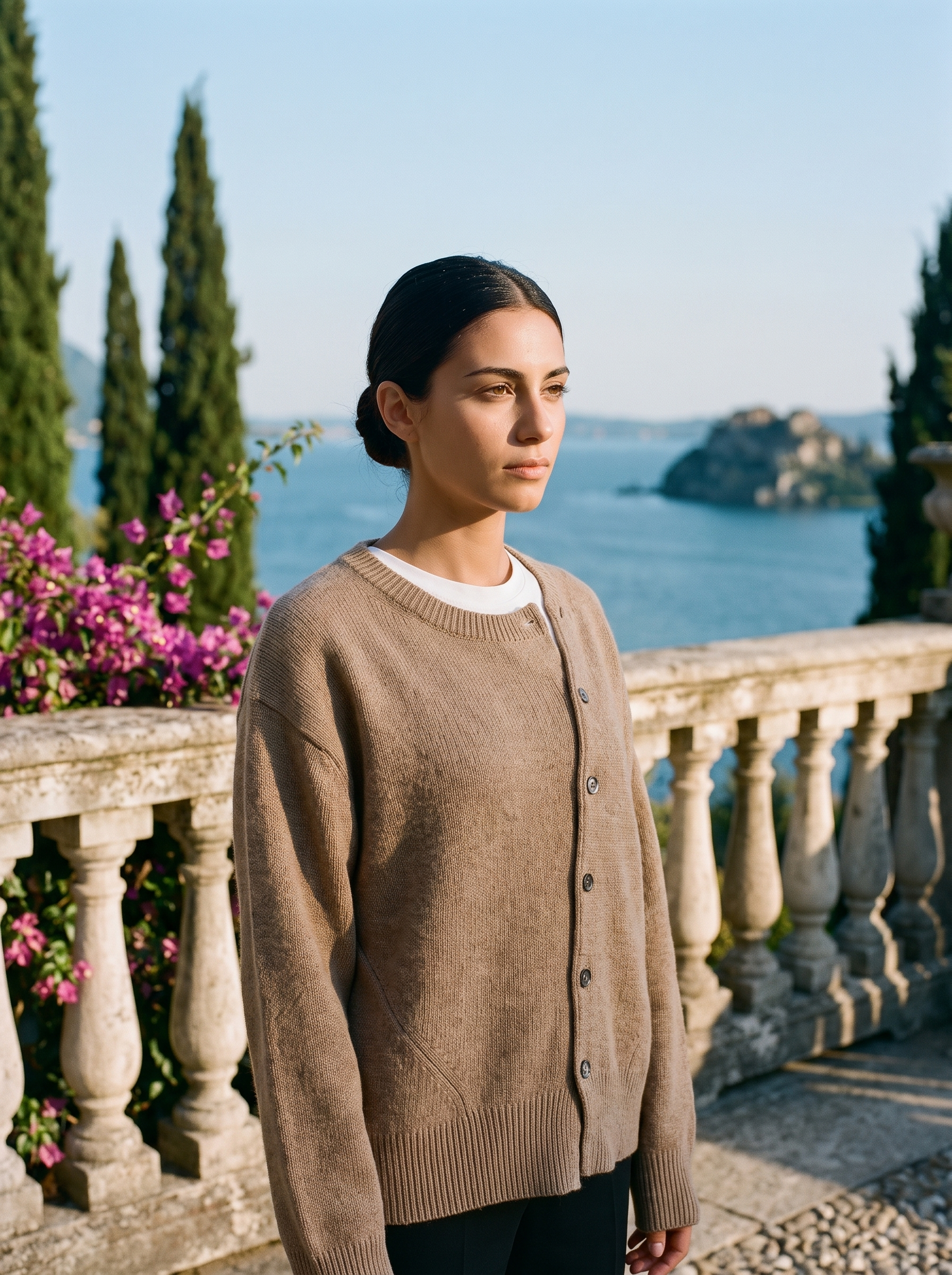 Woman wearing a brown knit cardigan on a terrace overlooking Lake Como, old money style — Aveloire