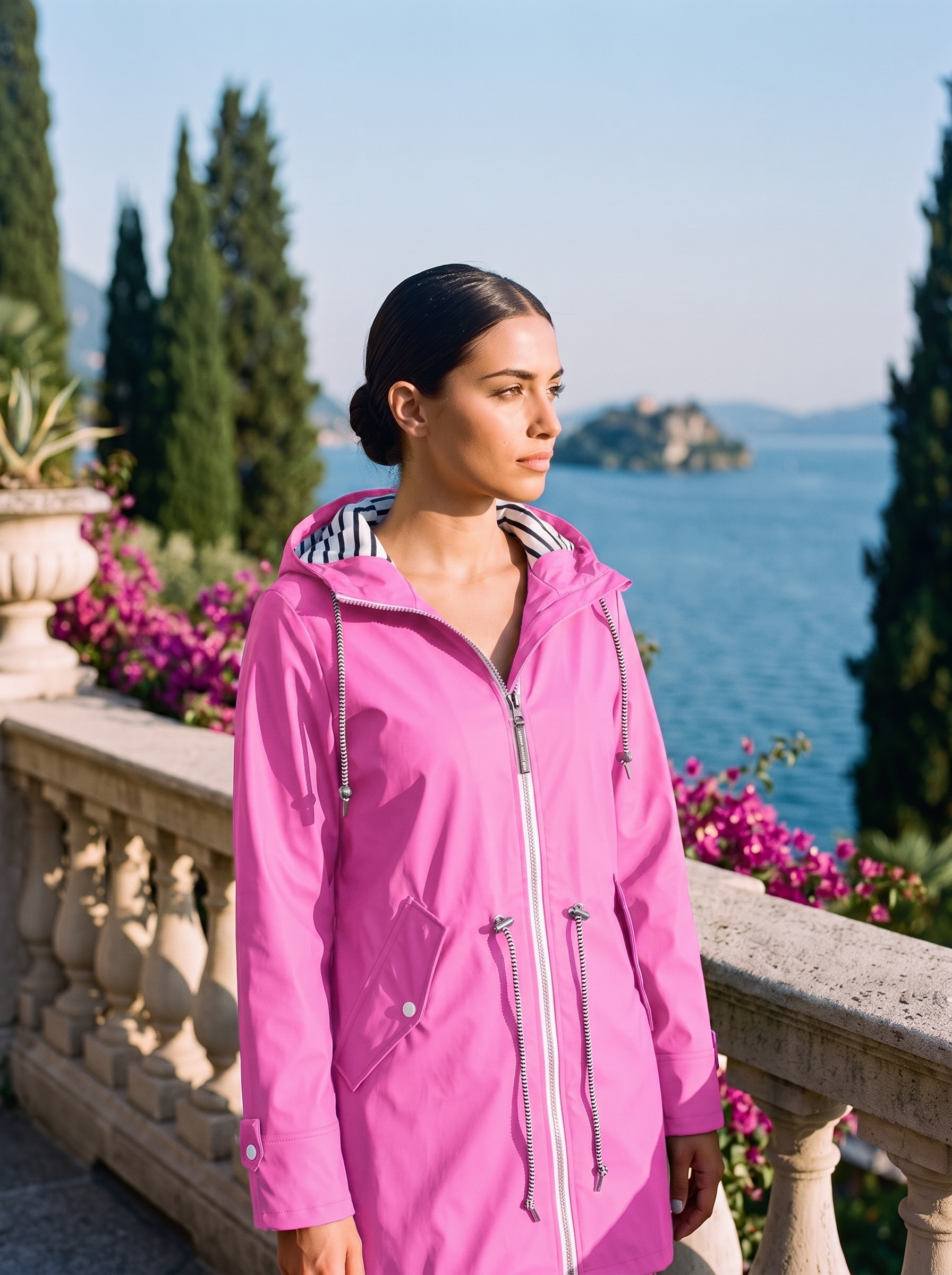 Woman wearing a bright pink hooded waterproof rain jacket on a Lake Como terrace — Aveloire