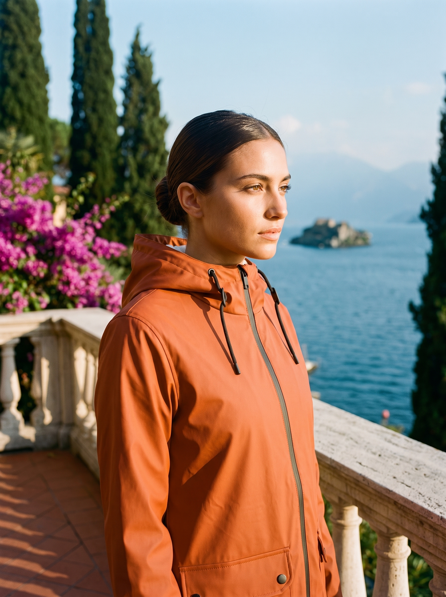 Woman wearing burnt orange waterproof rain jacket on a Lake Como terrace — Aveloire