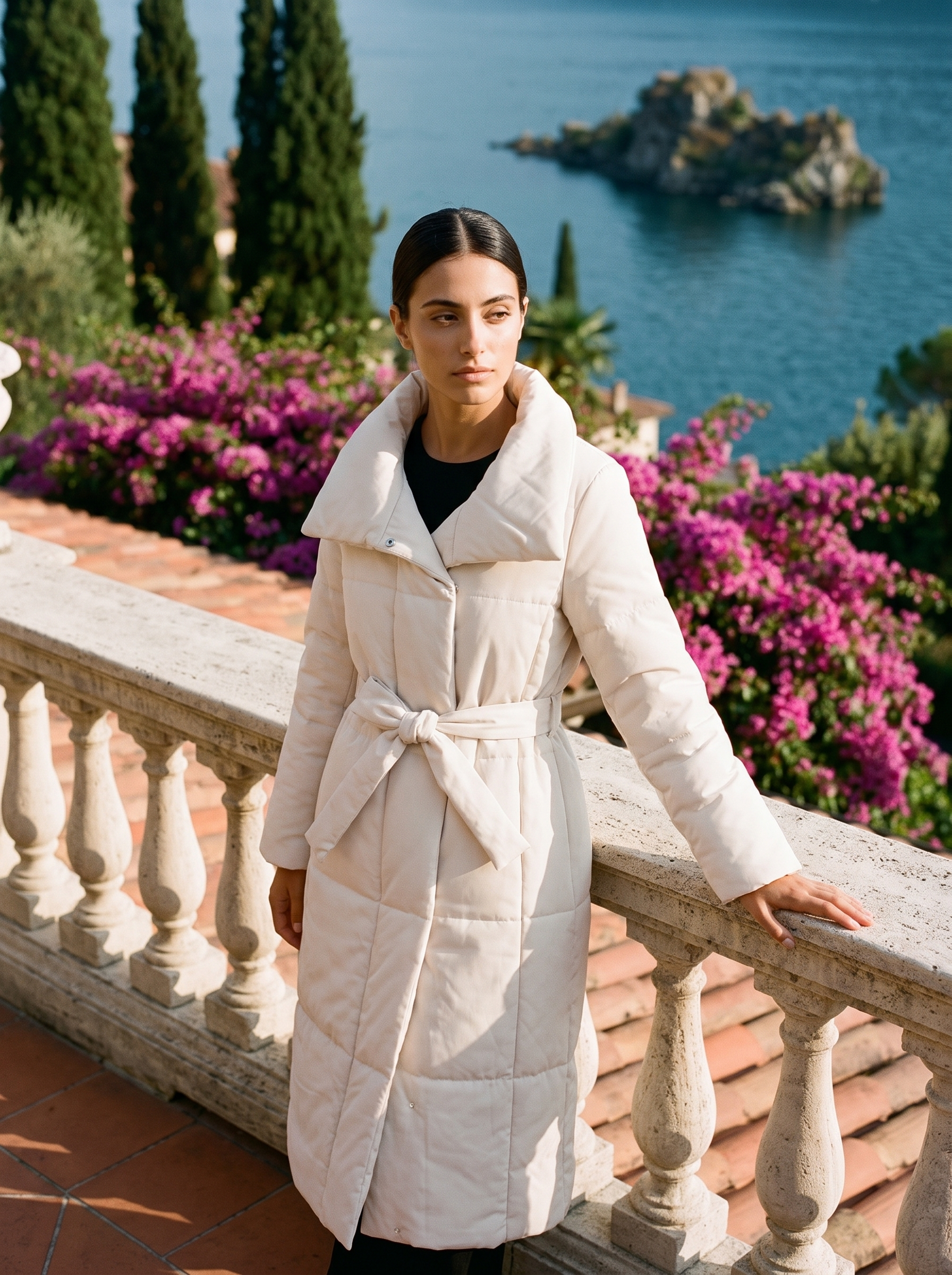 Woman wearing a cream longline belted quilted coat on a Lake Como terrace — Aveloire
