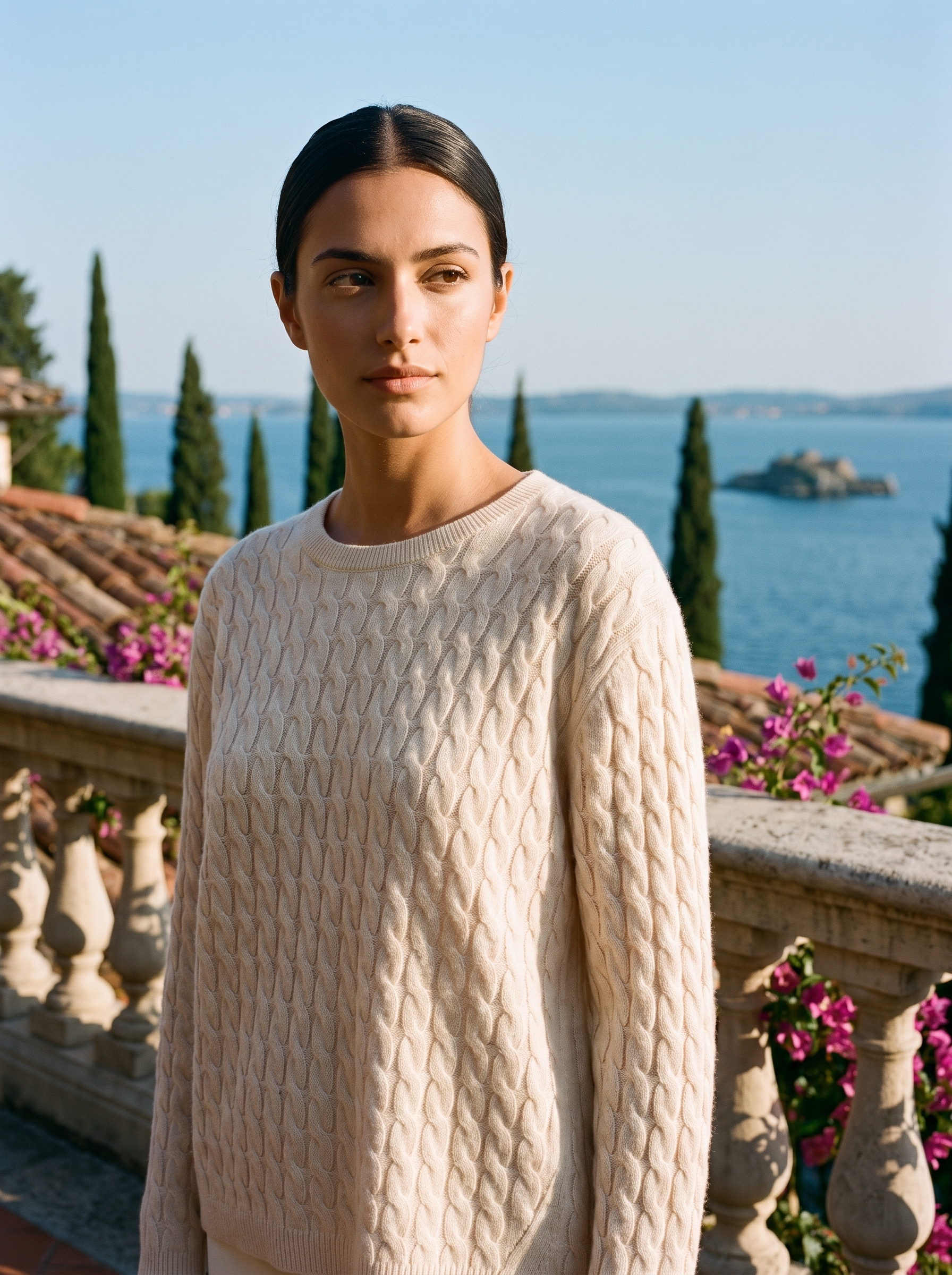 Woman wearing a cream cable-knit jumper on a terrace overlooking Lake Como, old money style — Aveloire