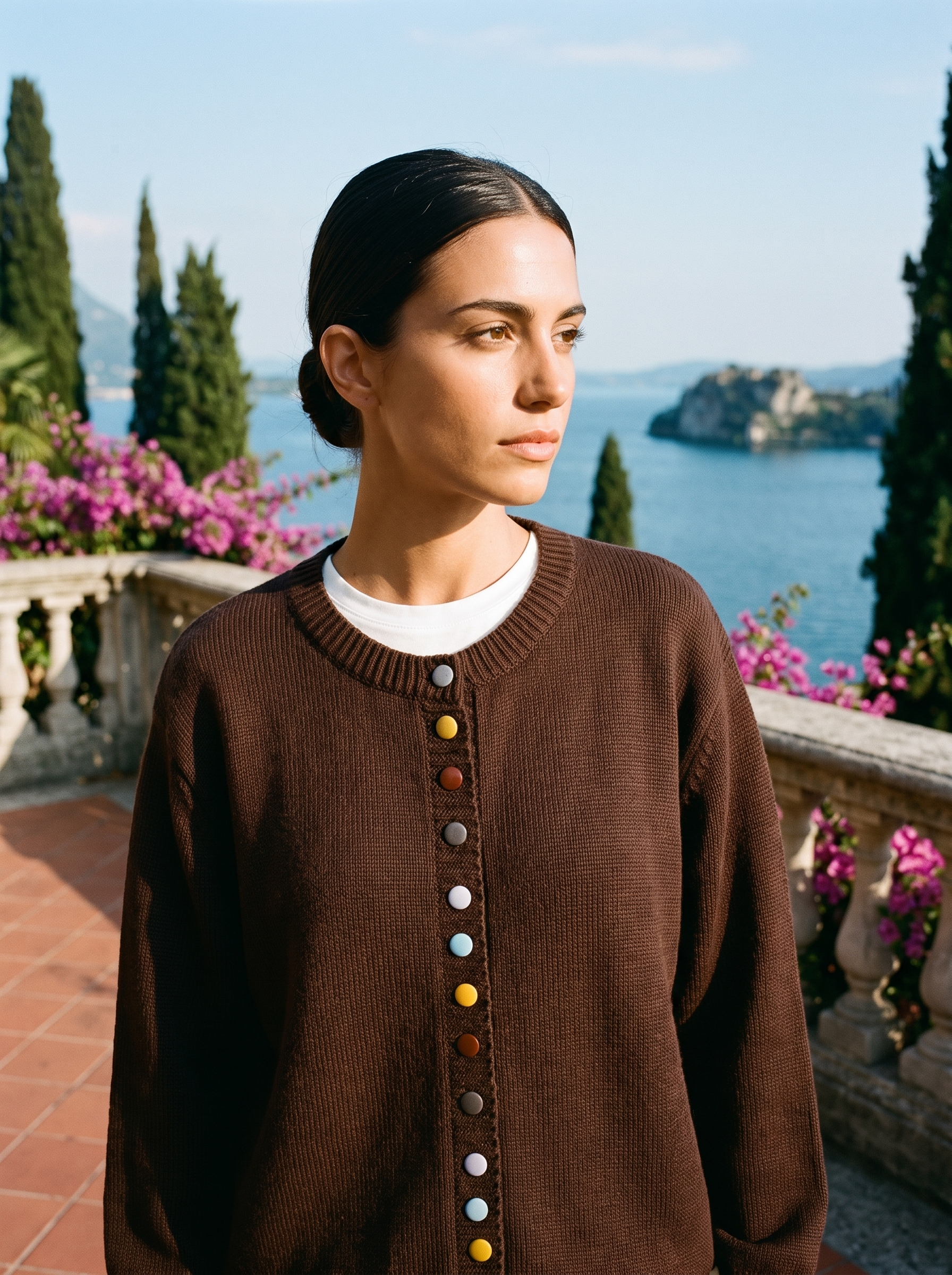 Woman wearing a dark brown button cardigan on a terrace overlooking Lake Como, old money style — Aveloire