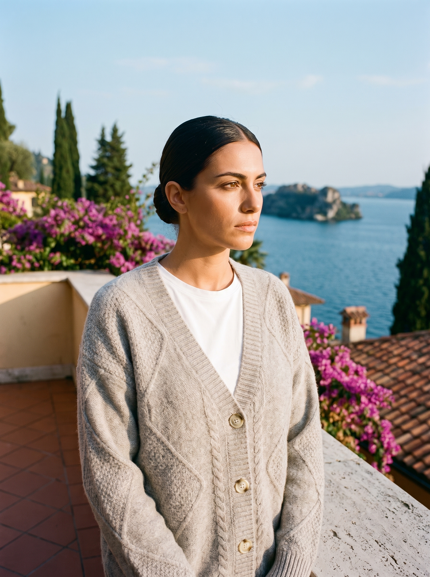Woman wearing a gray cable-knit cardigan on a terrace overlooking Lake Como, old money style — Aveloire
