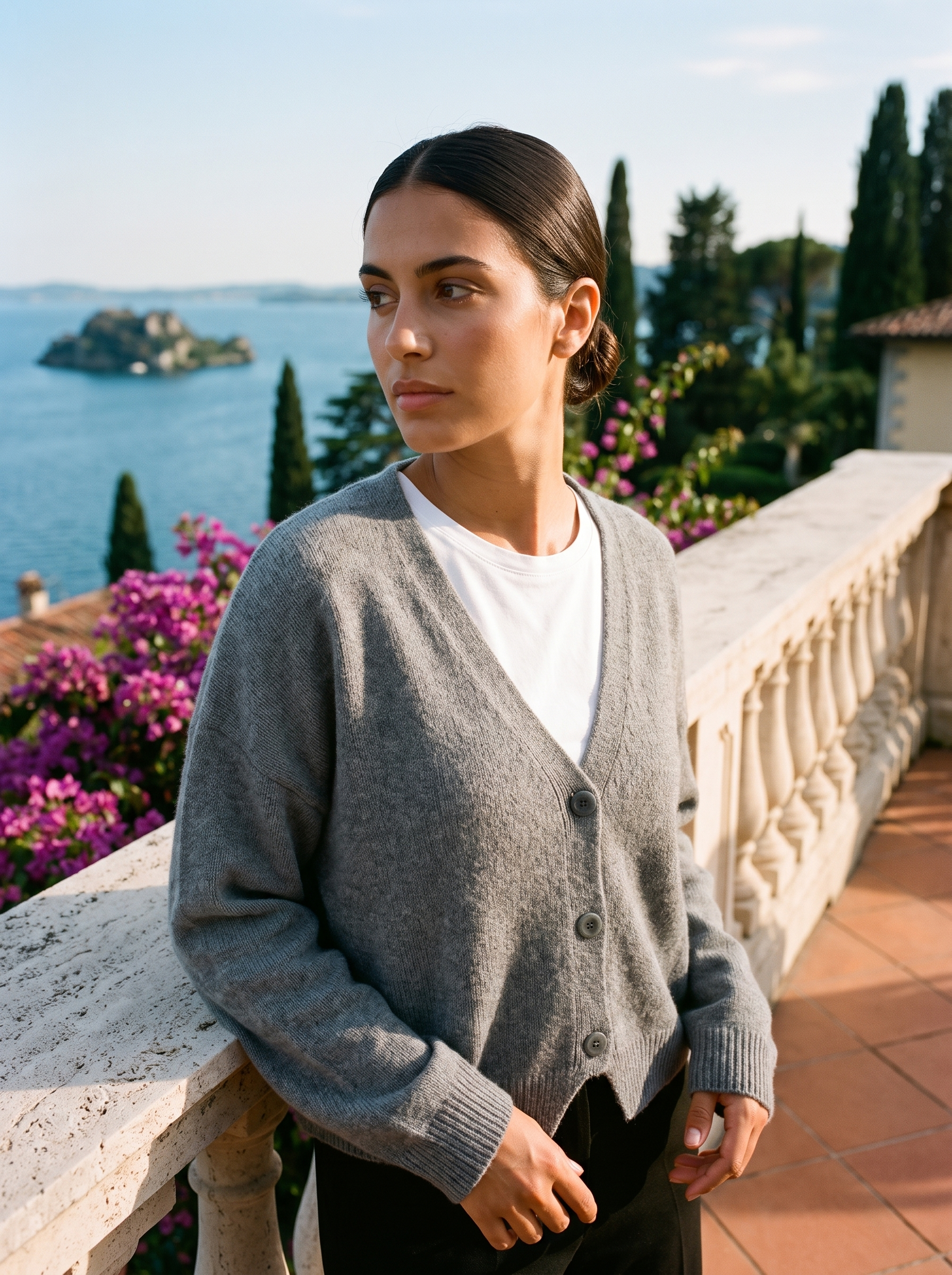 Woman wearing a gray V-neck cardigan on a terrace overlooking Lake Como, old money style — Aveloire