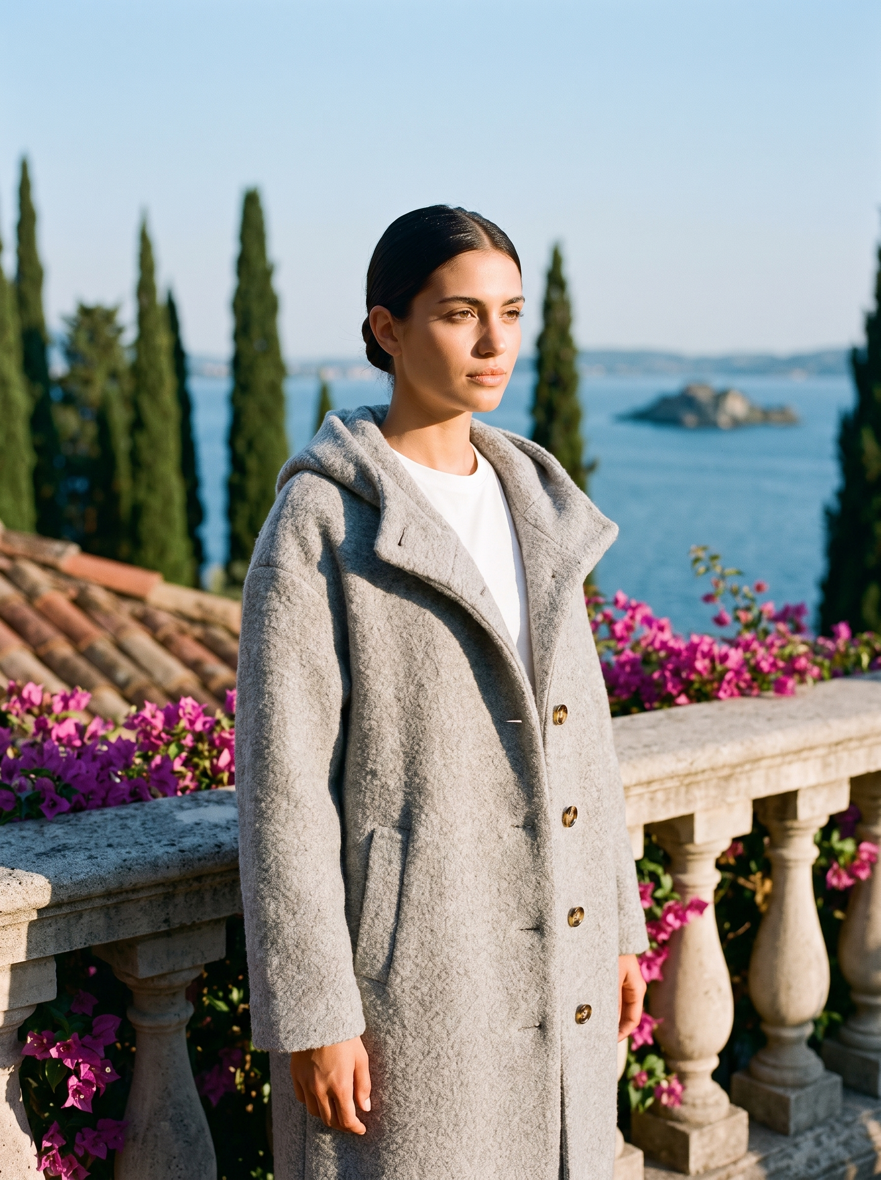Woman wearing a grey hooded wool coat on a terrace overlooking Lake Como — Aveloire