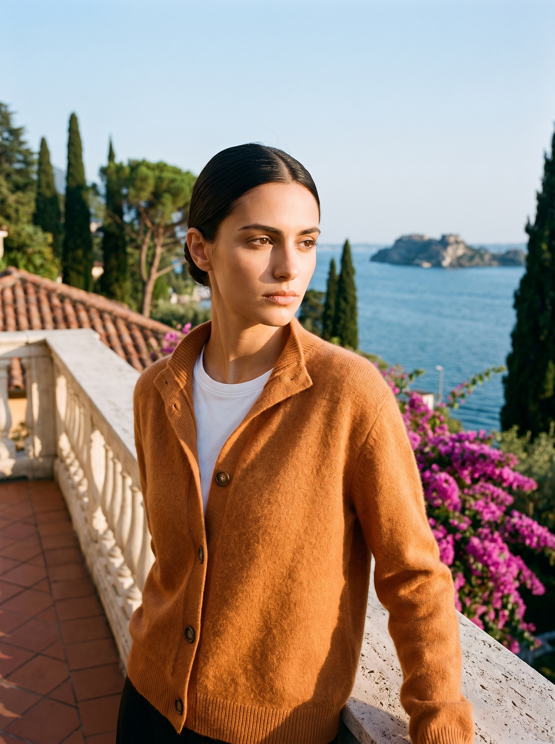 Woman wearing an orange stand-collar cardigan on a terrace overlooking Lake Como, old money style — Aveloire