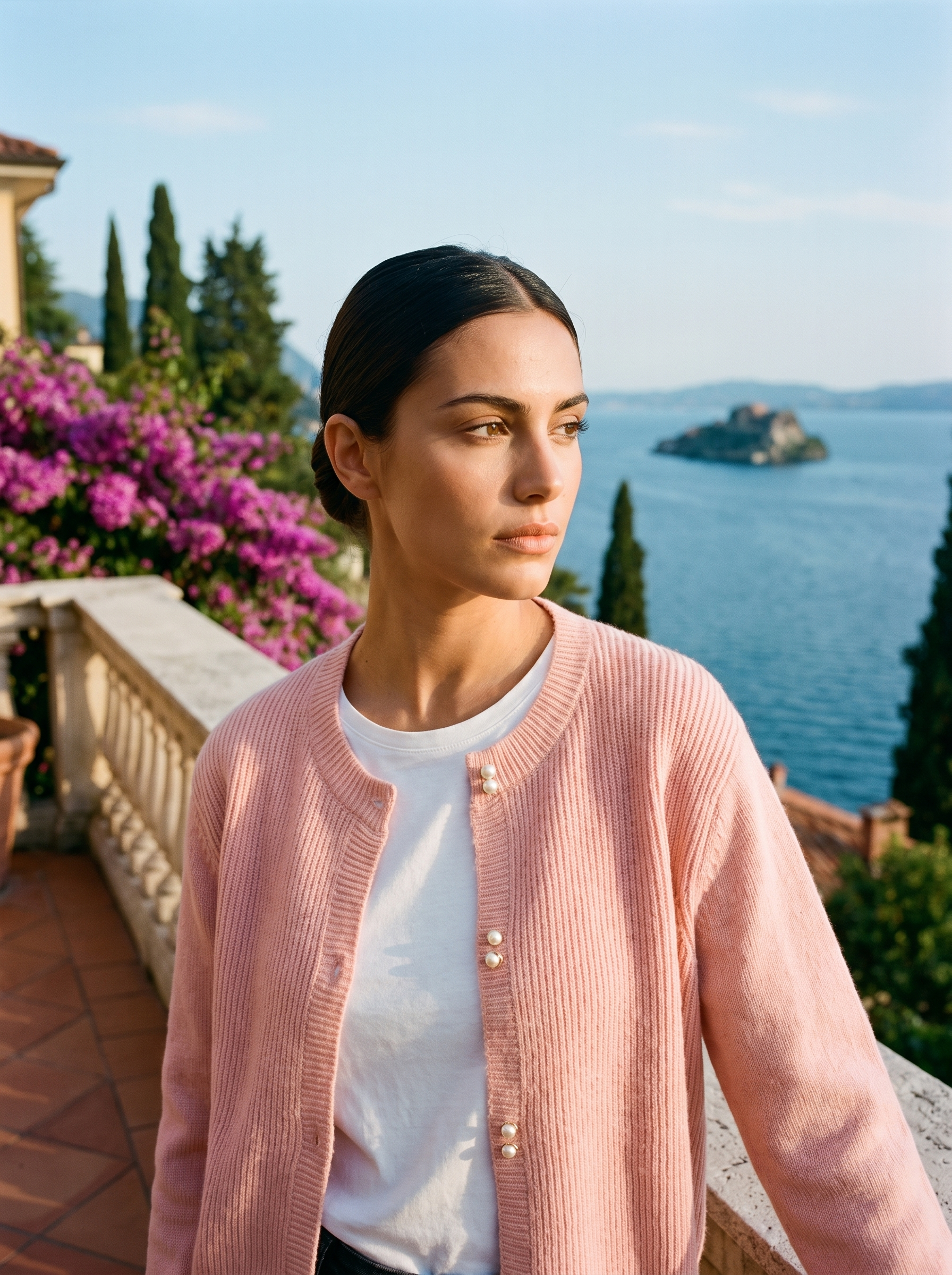 Woman wearing a pink round-neck cardigan on a terrace overlooking Lake Como, old money style — Aveloire