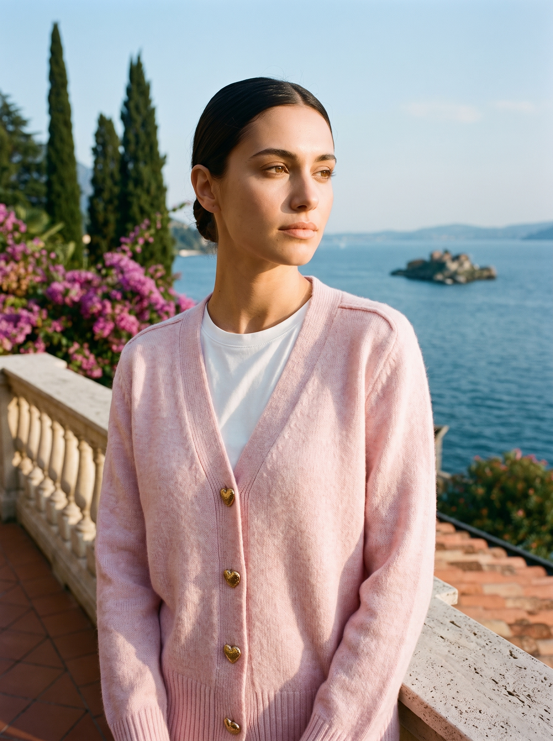 Woman wearing a pink V-neck button cardigan on a terrace overlooking Lake Como, old money style — Aveloire