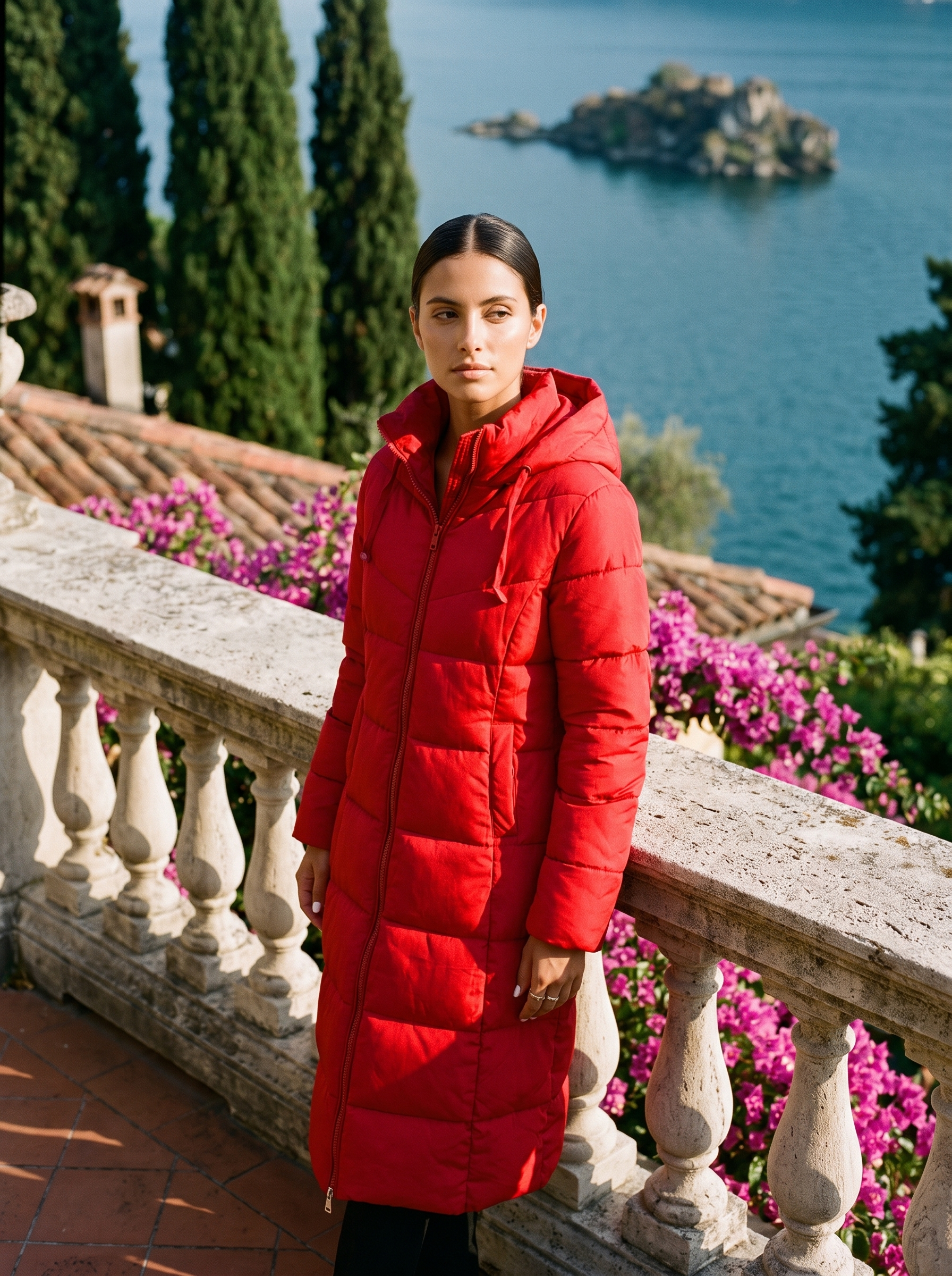 Woman wearing red longline hooded puffer coat on a Lake Como terrace