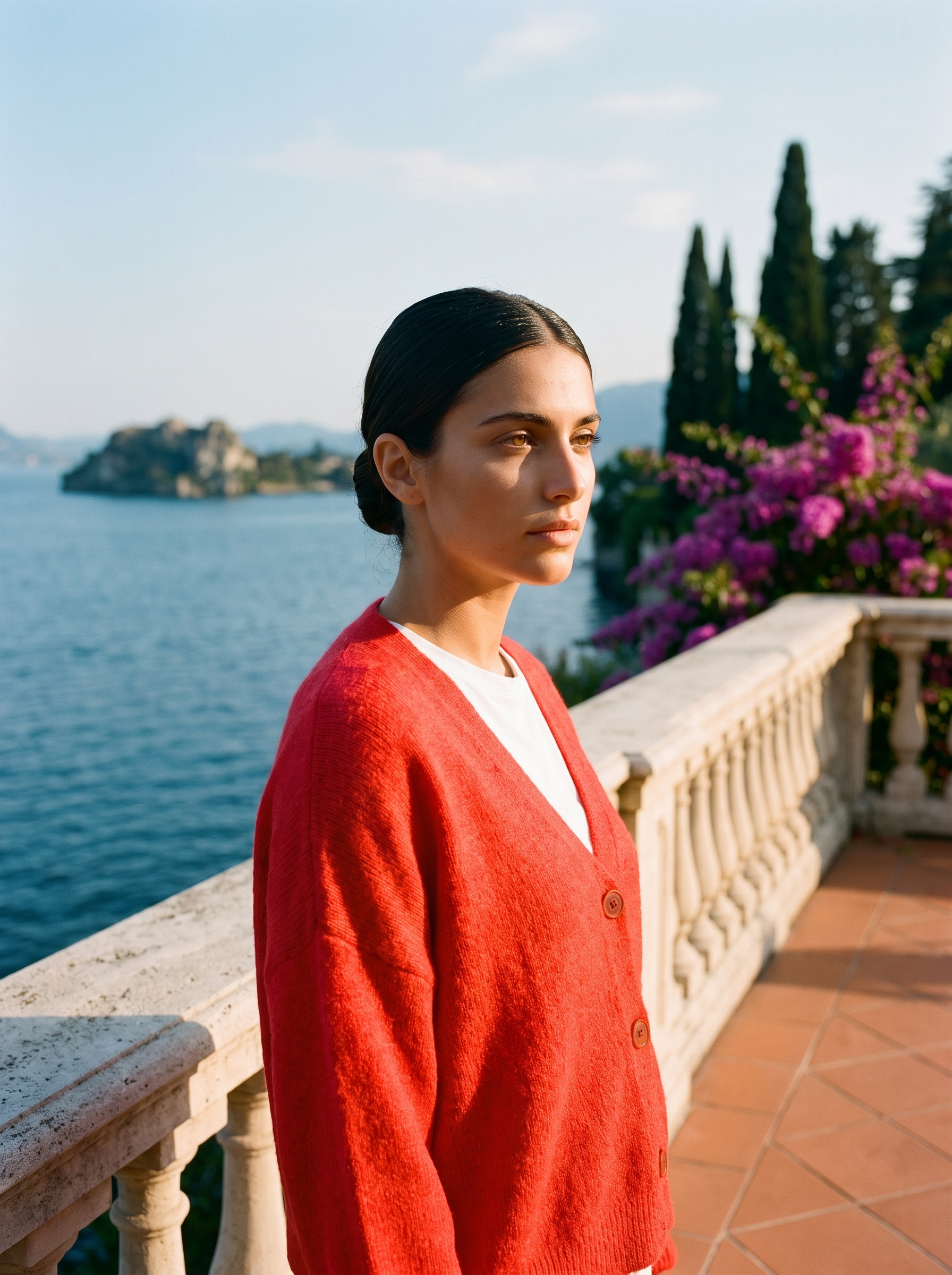 Woman wearing a red V-neck cardigan on a terrace overlooking Lake Como, old money style — Aveloire