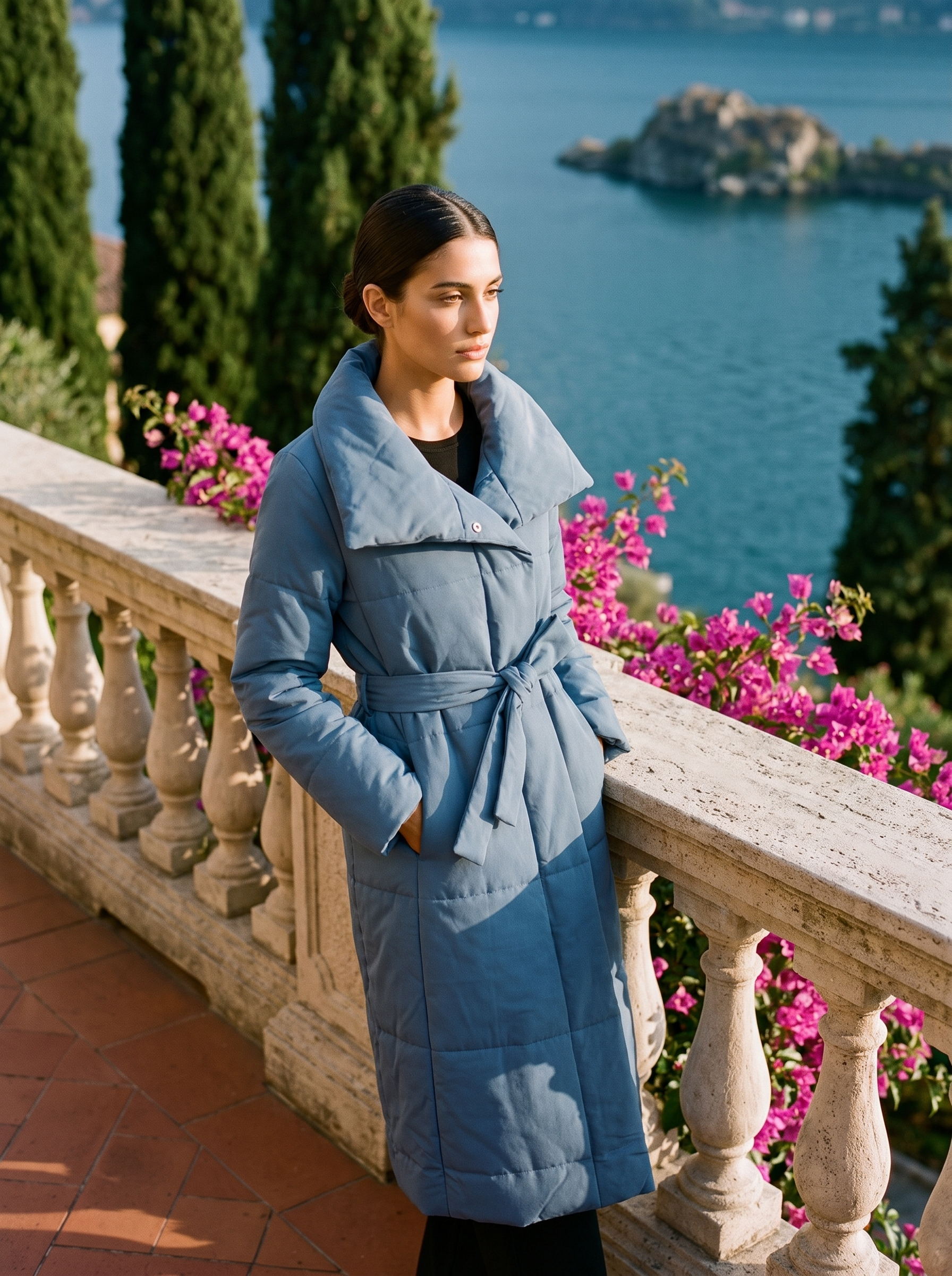 Woman wearing a slate-blue belted quilted coat on a Lake Como terrace — Aveloire