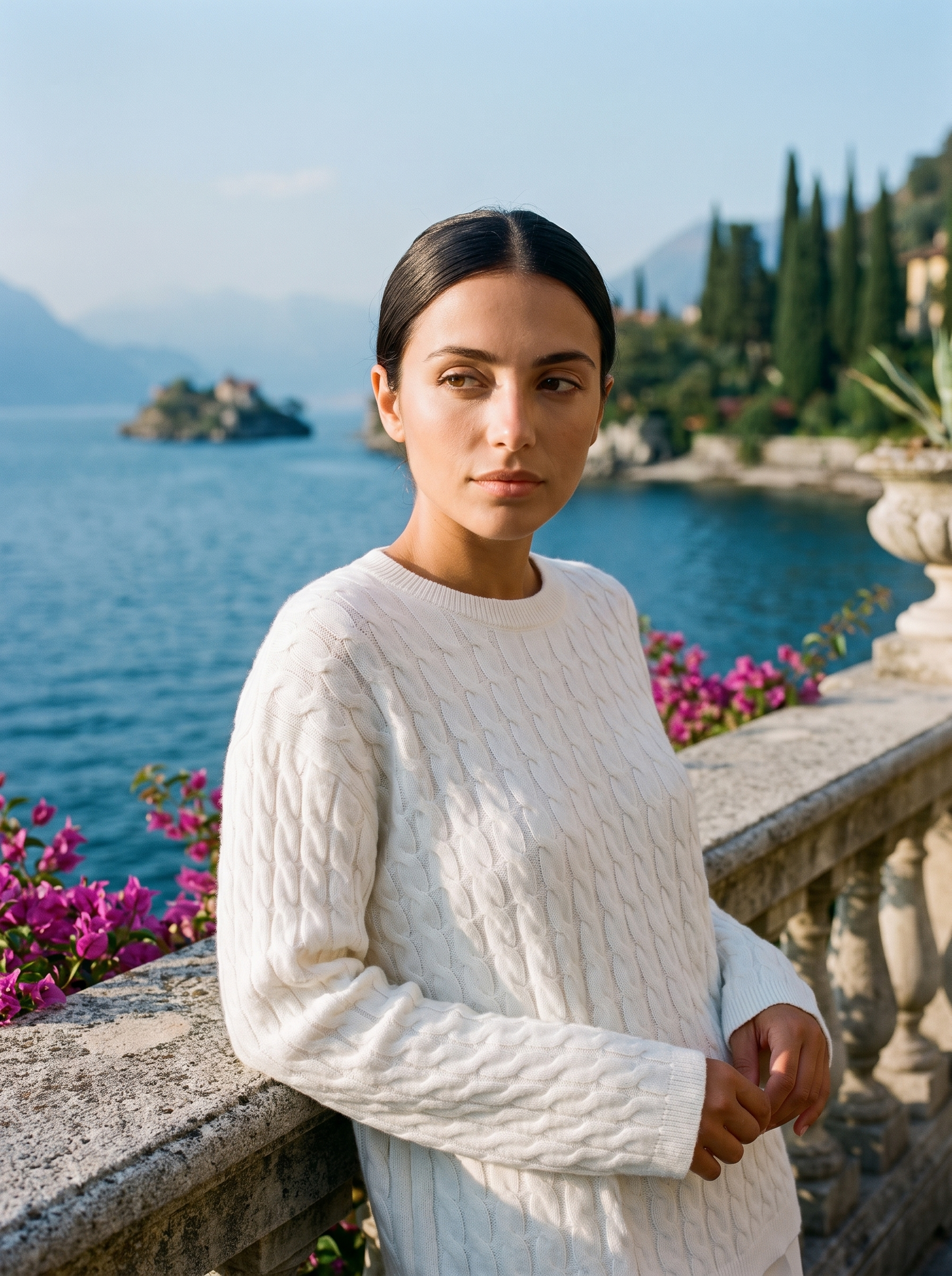 Woman wearing a white cable-knit jumper on a terrace overlooking Lake Como — Aveloire